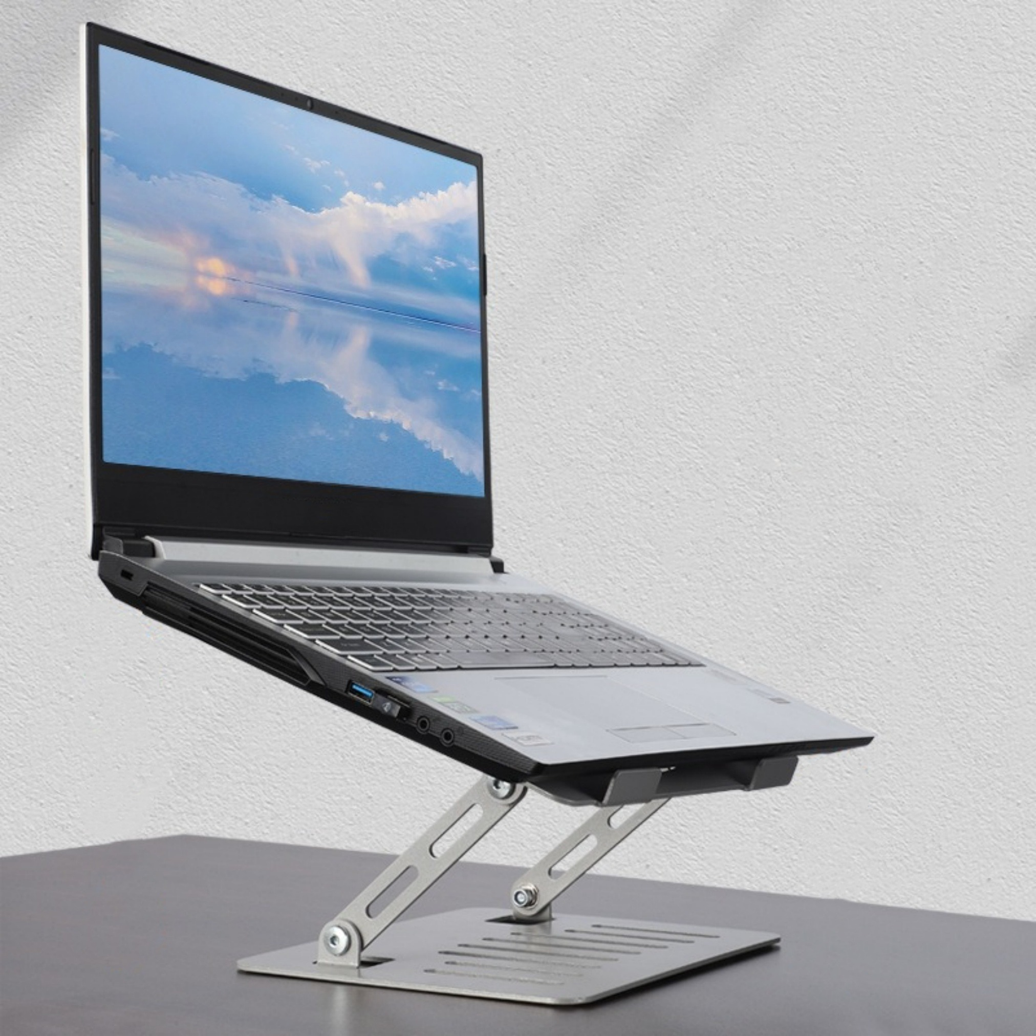 Ein Laptop auf einem silbernen Laptopständer, nach oben abgewinkelt, vor weißem Hintergrund.