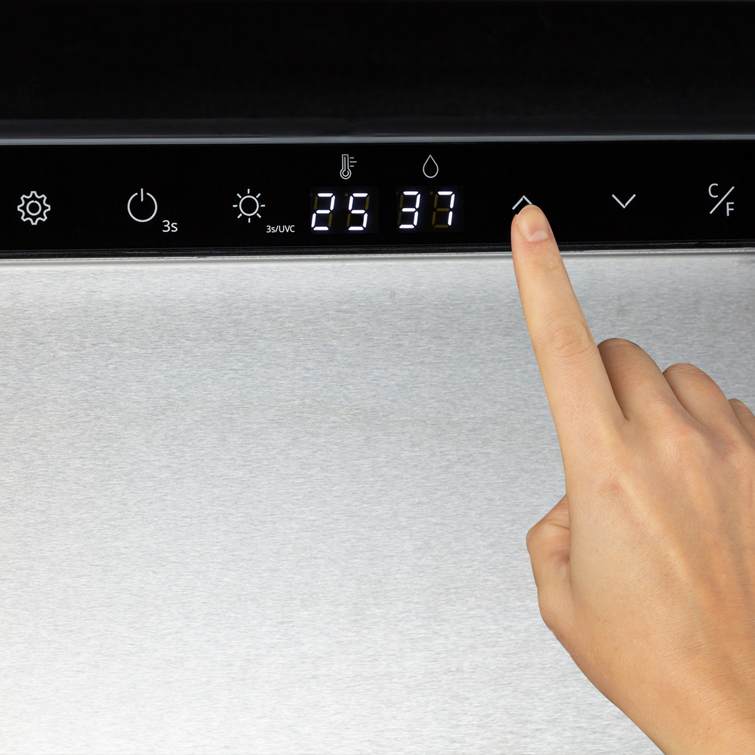 Un dito tocca un pannello di controllo con numeri e simboli. Il pannello è in acciaio inox.