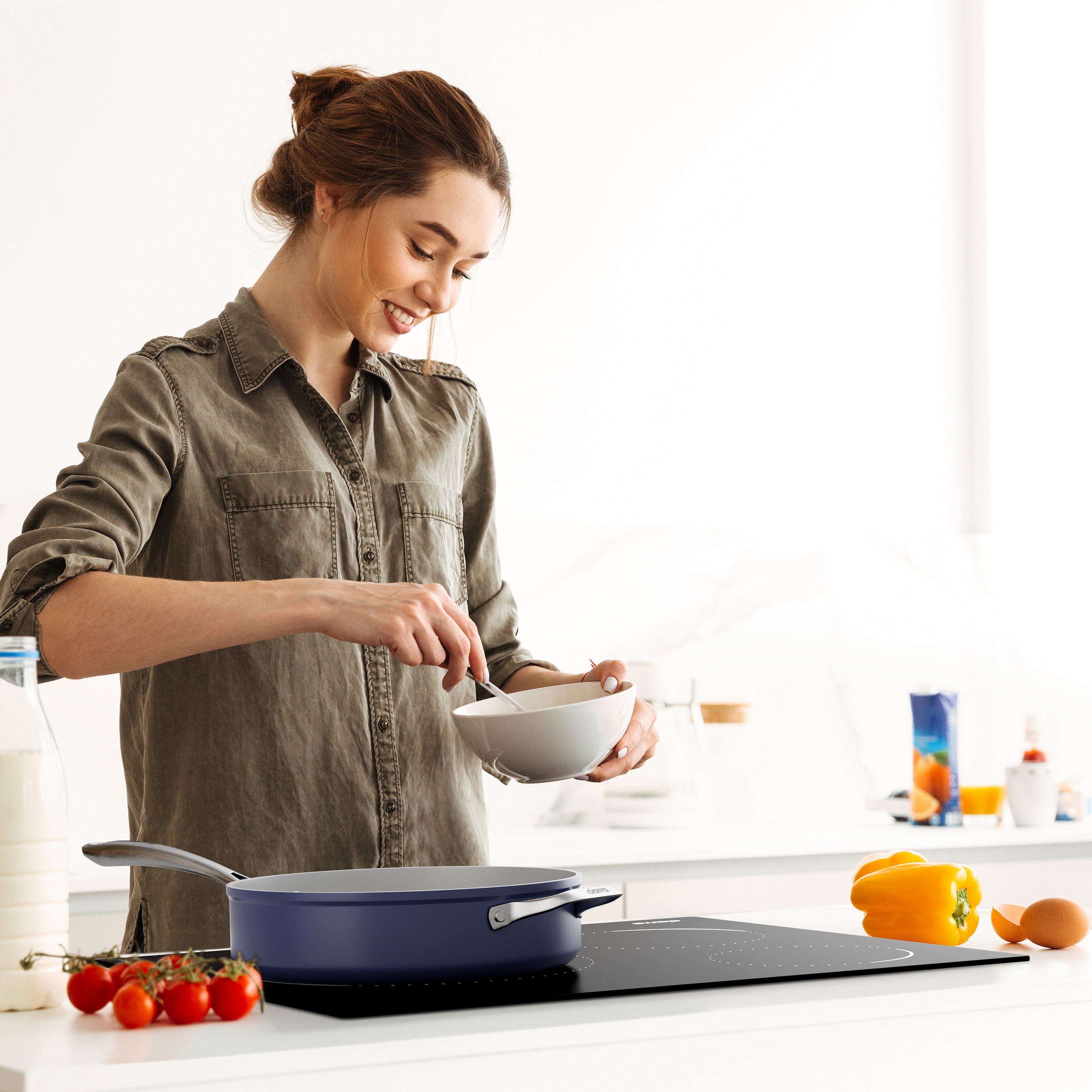 Woman cooks in a kitchen, stirring in a bowl. Vegetables and a pan are on the stove.