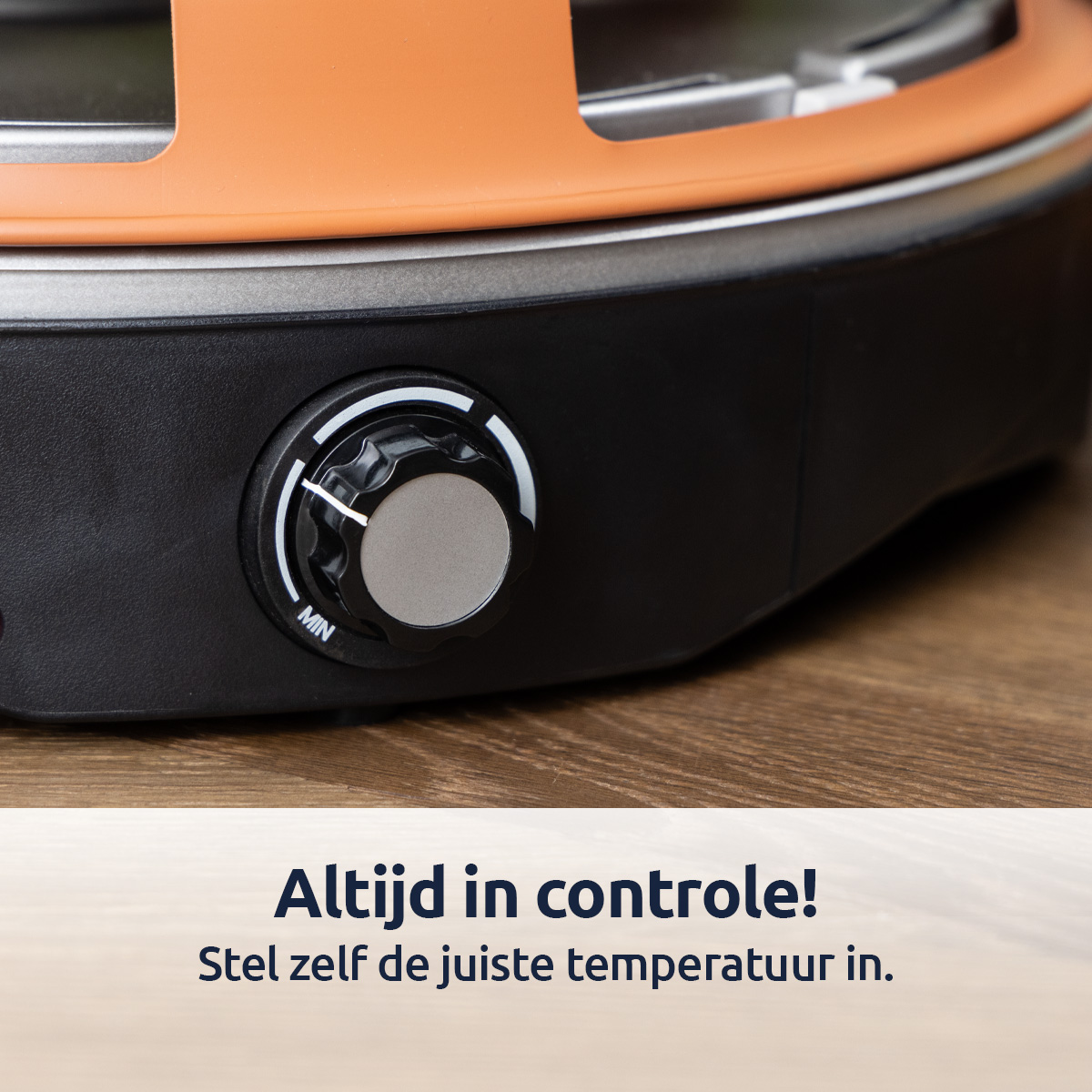 Gros plan sur un bouton noir d'un appareil de cuisson. Dessus orange. Fond en bois.
