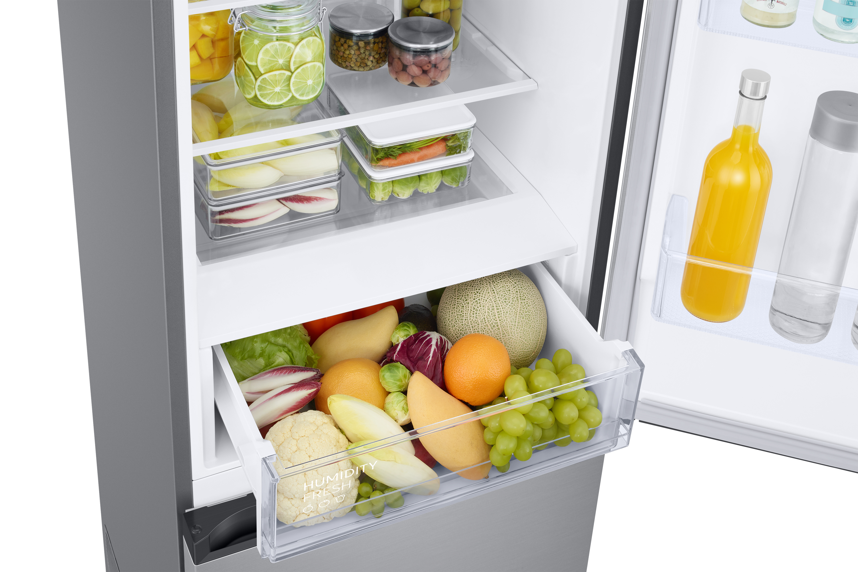 Interno del frigorifero: cassetto con frutta e verdura, ripiani con alimenti e una bottiglia.