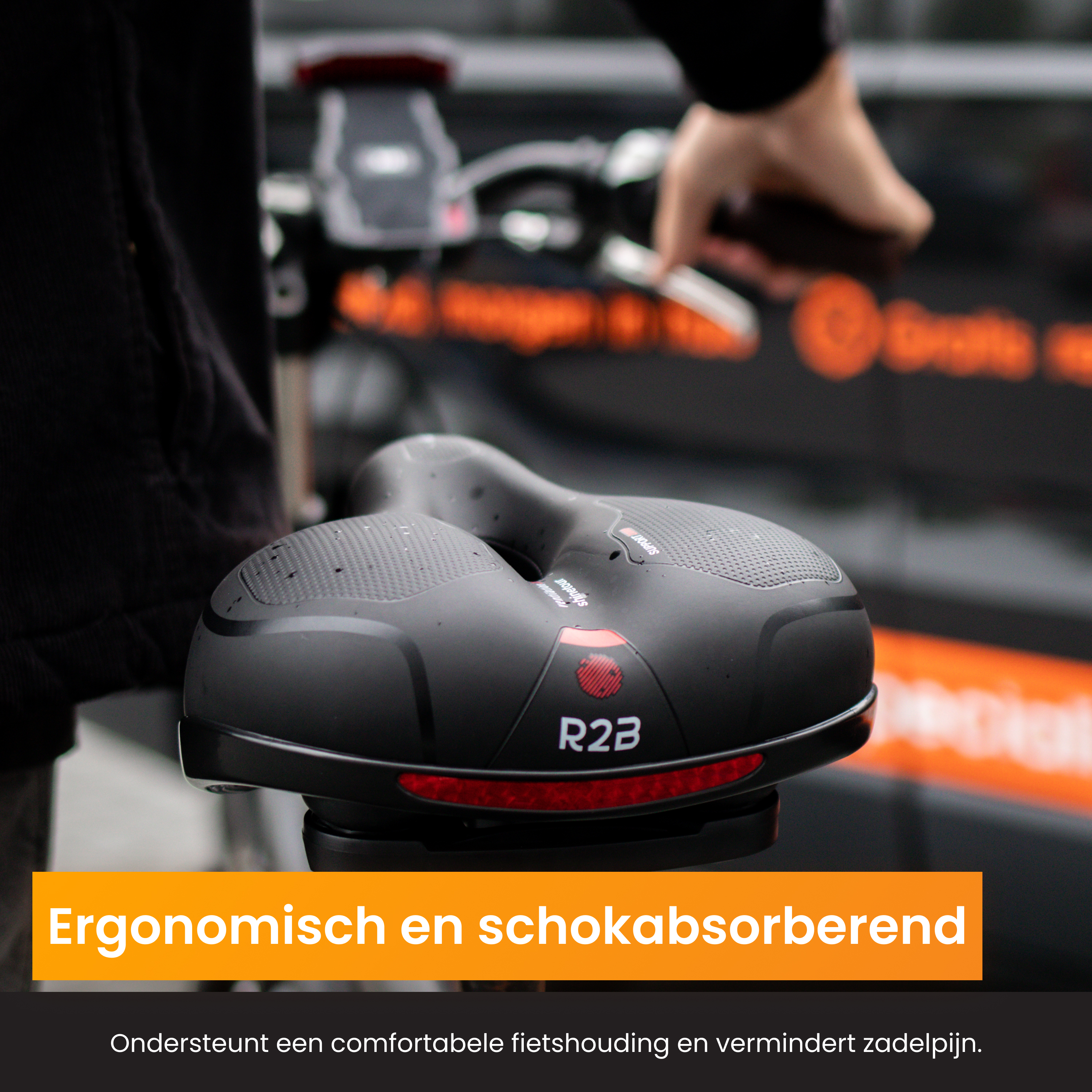 Zwart fietszadel met rode accenten, tekst 'Ergonomisch en schokabsorberend'.