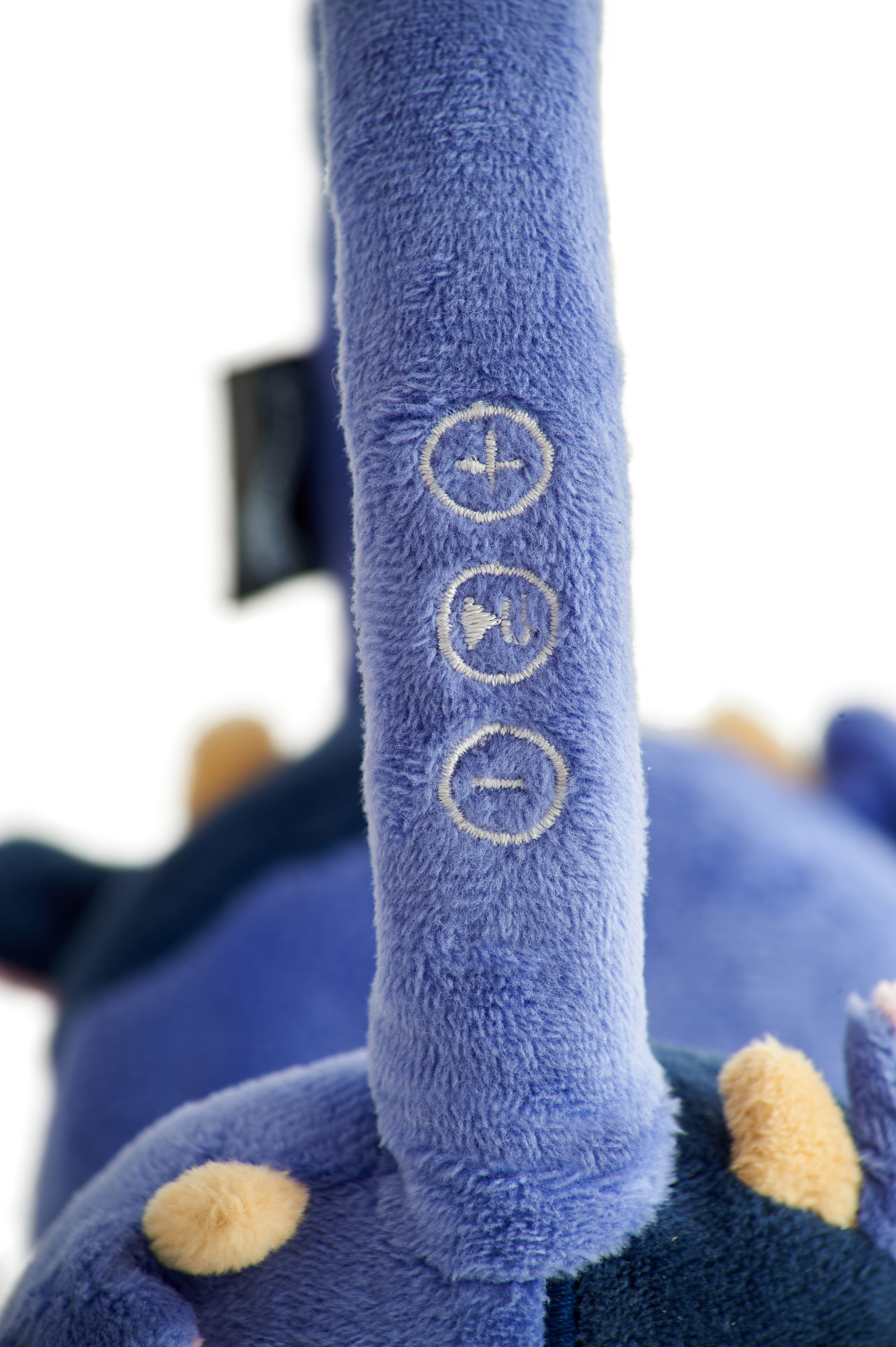 Close-up van een blauwe pluche koptelefoon met volume- en afspeelknoppen.