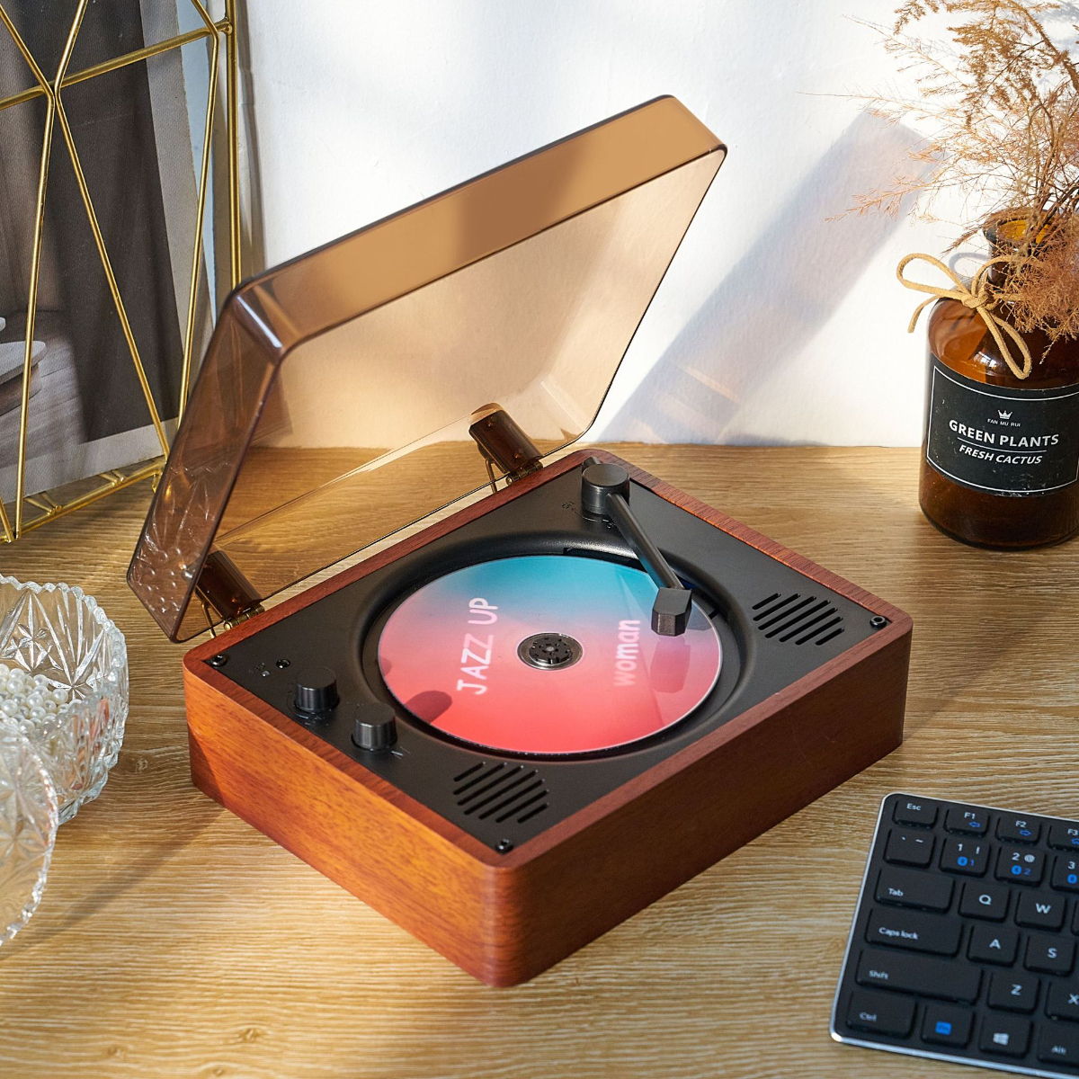 Vintage-Plattenspieler mit Schallplatte. Holzgehäuse, brauner Deckel. Tastatur und Pflanze im Hintergrund.