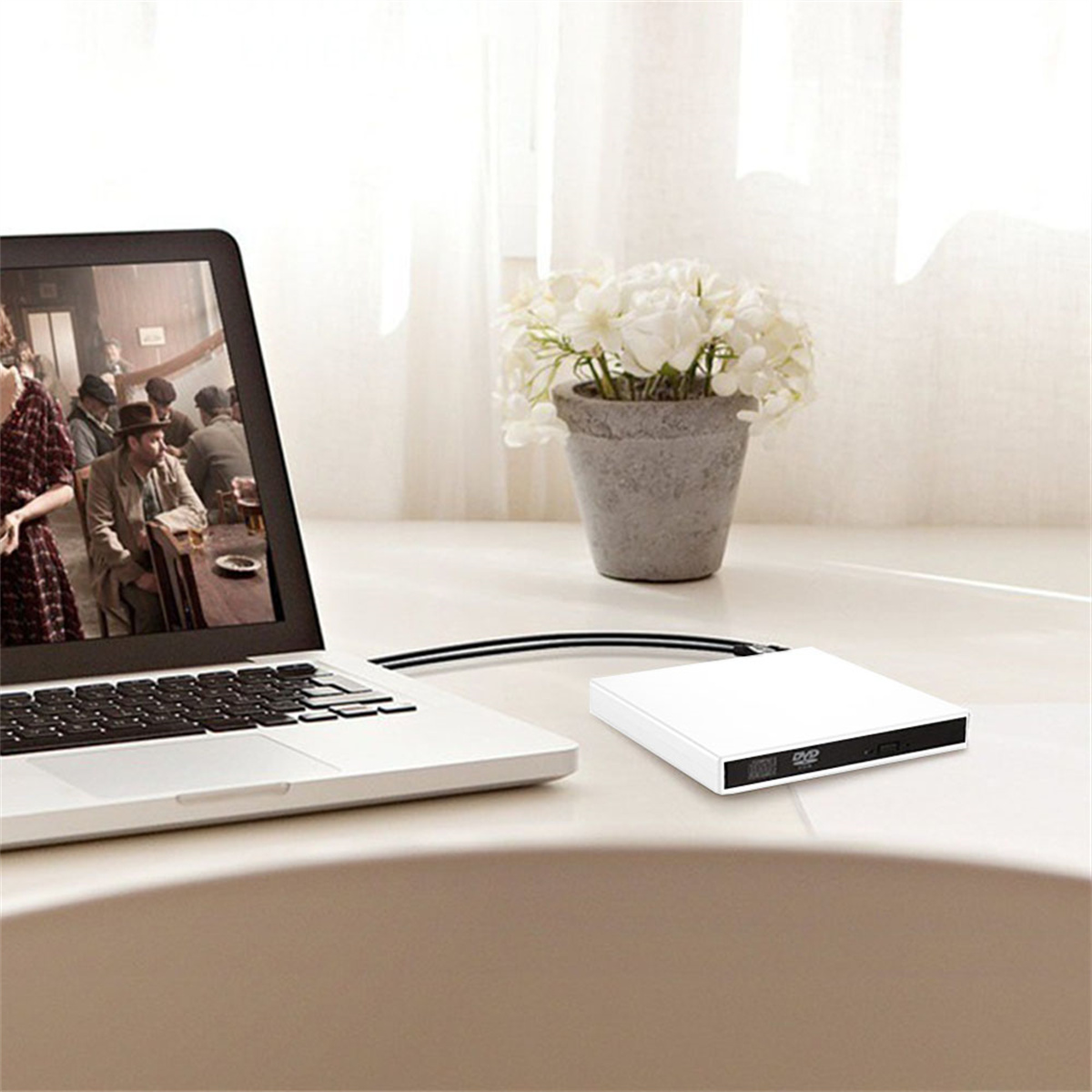 Ein Laptop mit einem Film, neben einem DVD-Player und Blumen.