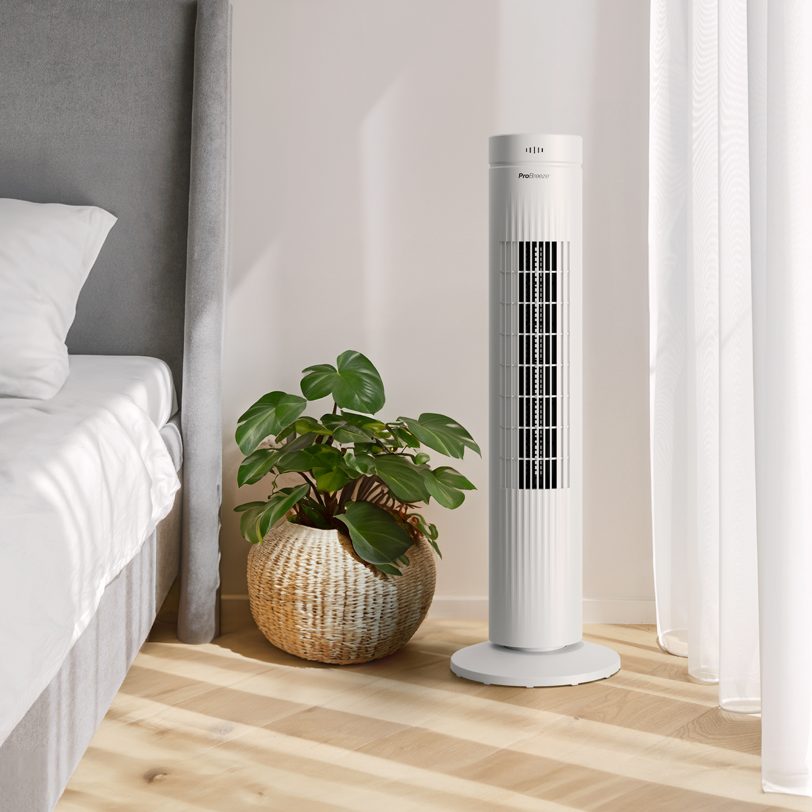 Weißer Turmventilator und Topfpflanze in einem Schlafzimmer. Der Ventilator ist hoch und vertikal.