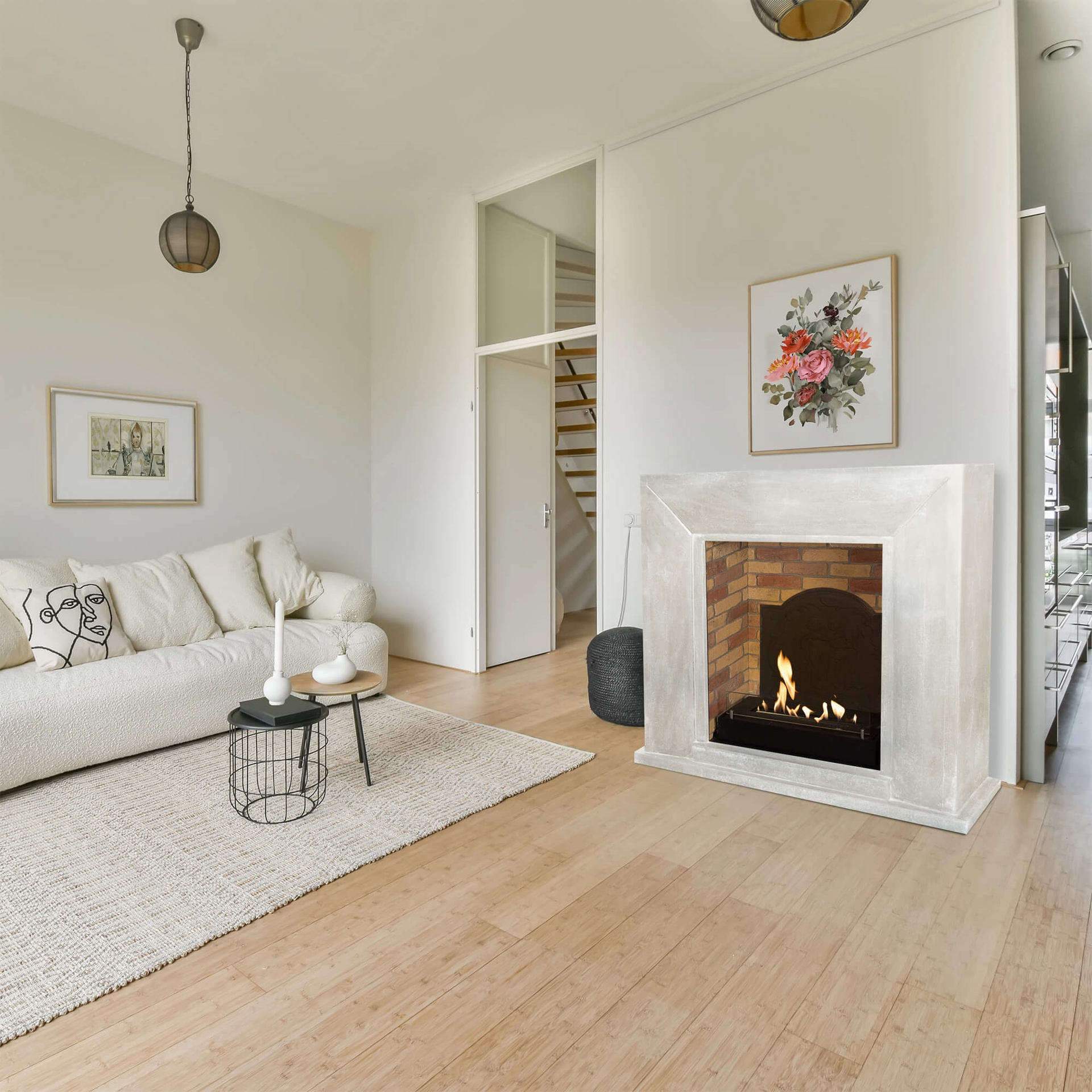 Woonkamer met witte bank, open haard, houten vloer, vloerkleed en een bloemenfoto boven de open haard.