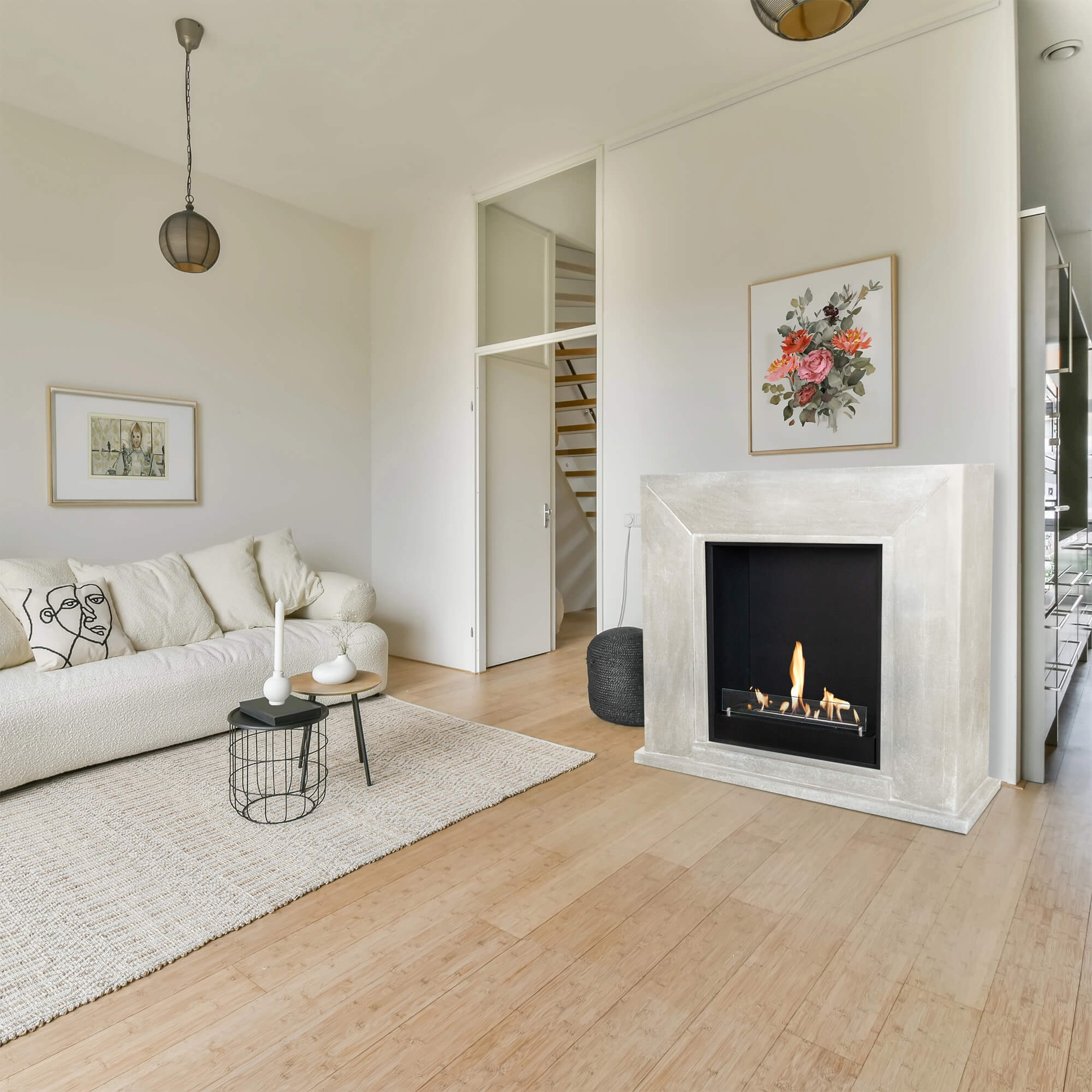 Living room with fireplace. White sofa, rug, two tables, and a painting. Wooden floor. Decorative lights hanging from the ceiling.