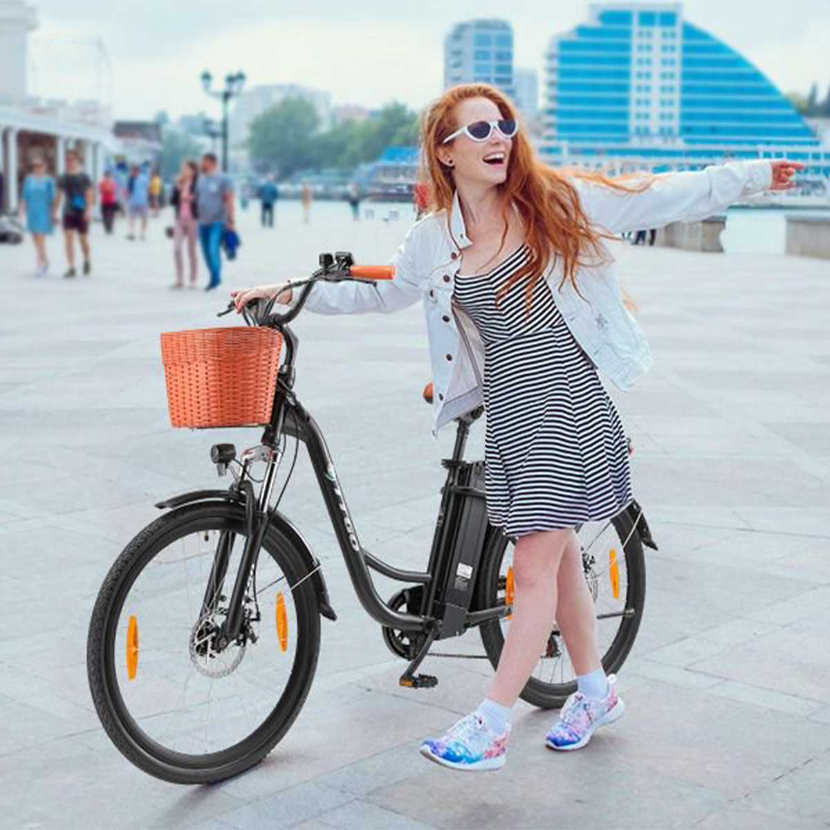 Kobieta na czarnym rowerze z koszykiem, uśmiechnięta, pozująca na ulicy miasta.