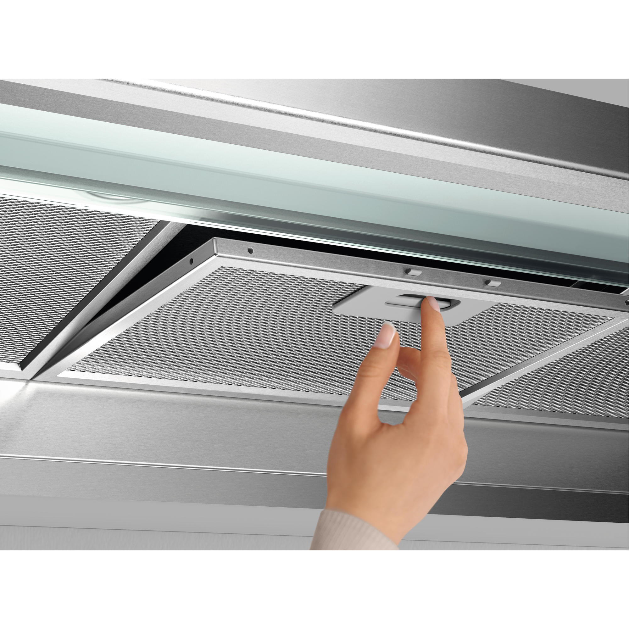 Una mano apre un filtro su una cappa da cucina, in acciaio inox.