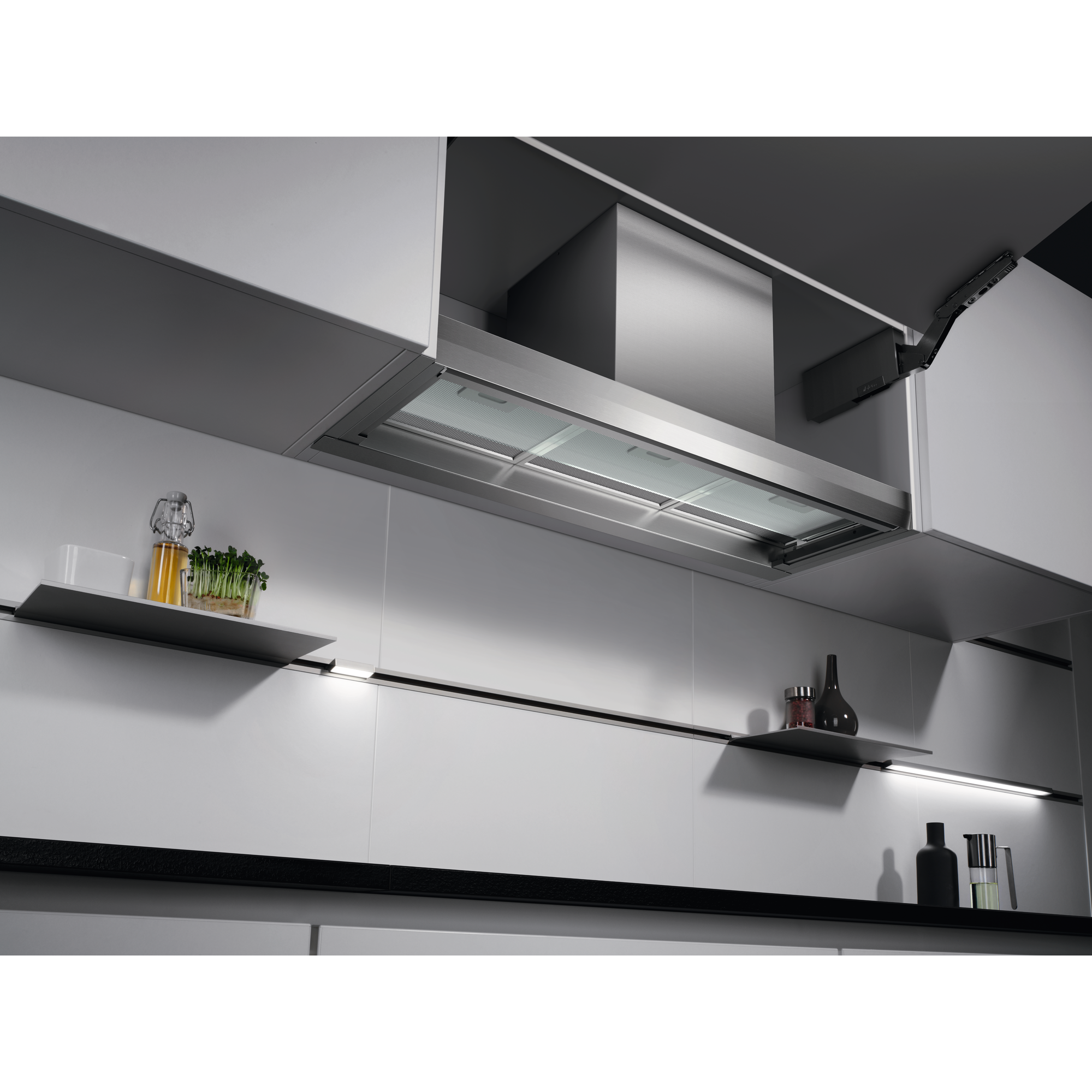 Cucina moderna con una cappa. Sono visibili anche mensole e luci.