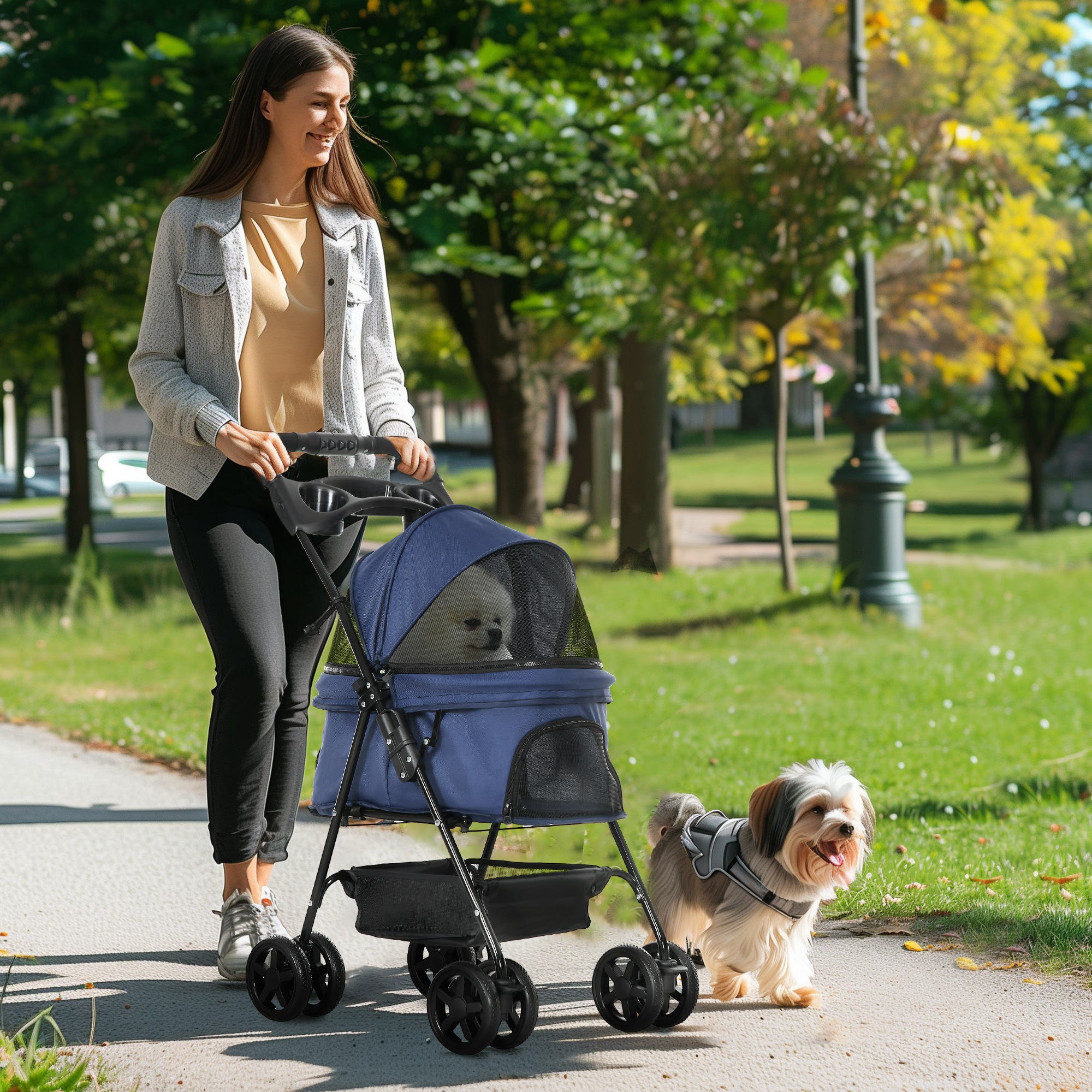 Mujer empujando un cochecito azul para mascotas con un perro caminando a su lado.