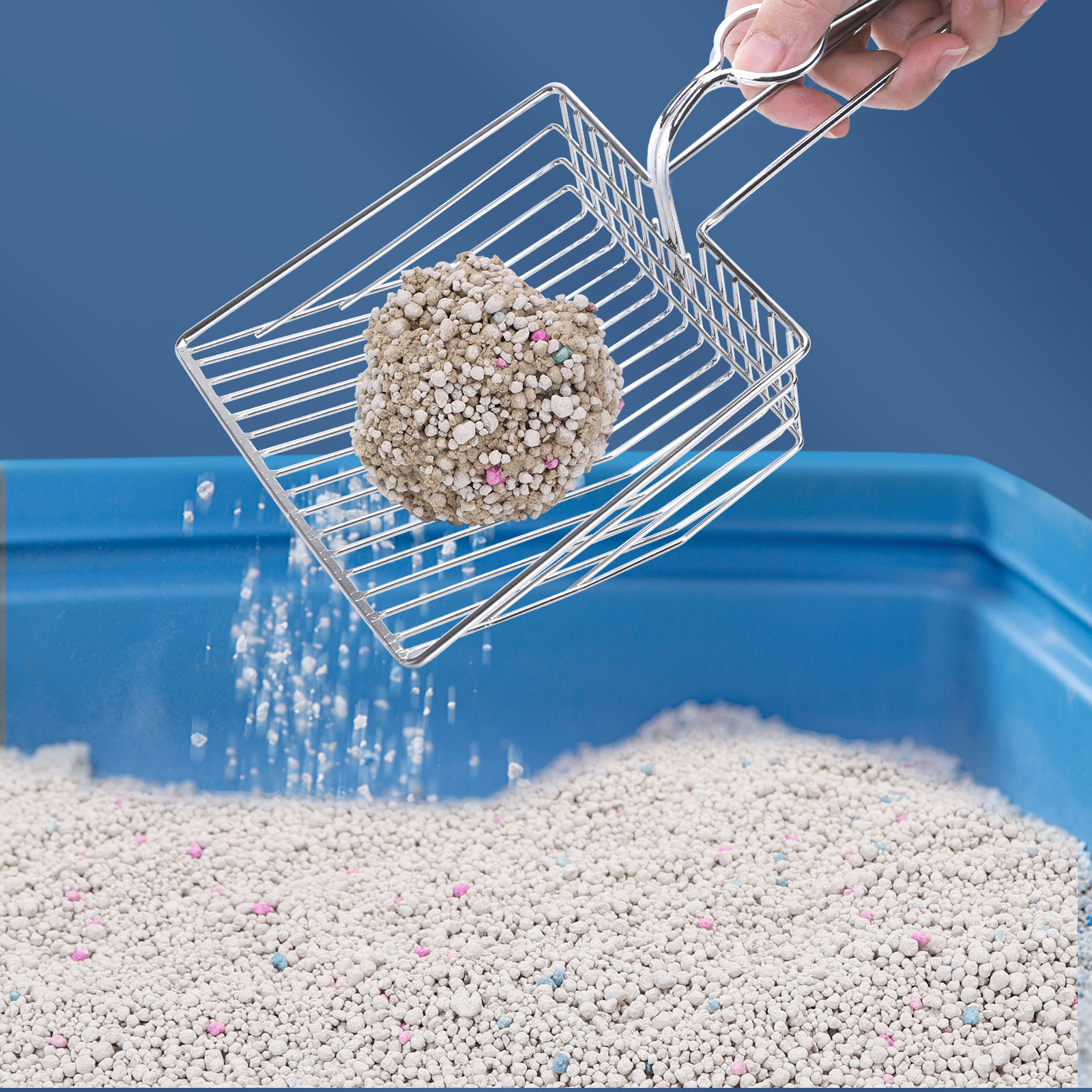 Pala metálica para arena de gato con un grumo y arena cayendo en una caja azul.