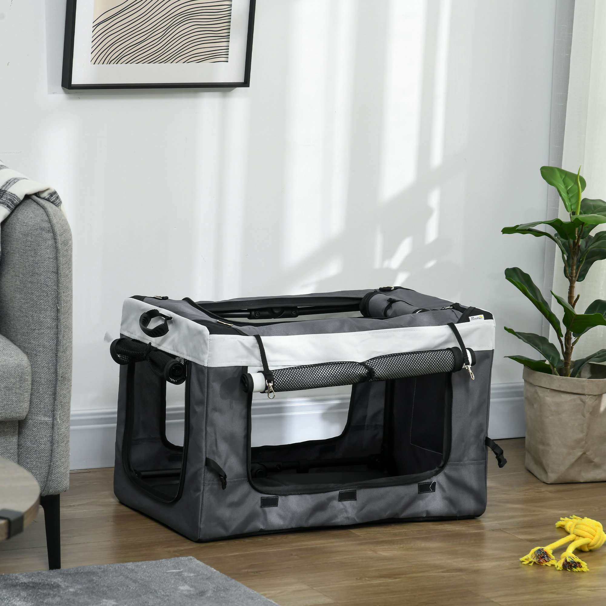 Un transportín gris y blanco para mascotas dentro de una habitación, con un juguete para perros cerca.