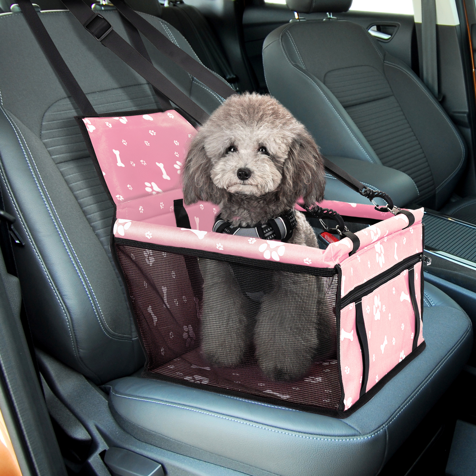Asiento rosa para coche para mascotas con un perro dentro. El asiento tiene huellas de patas y patrones de huesos. El perro es gris.