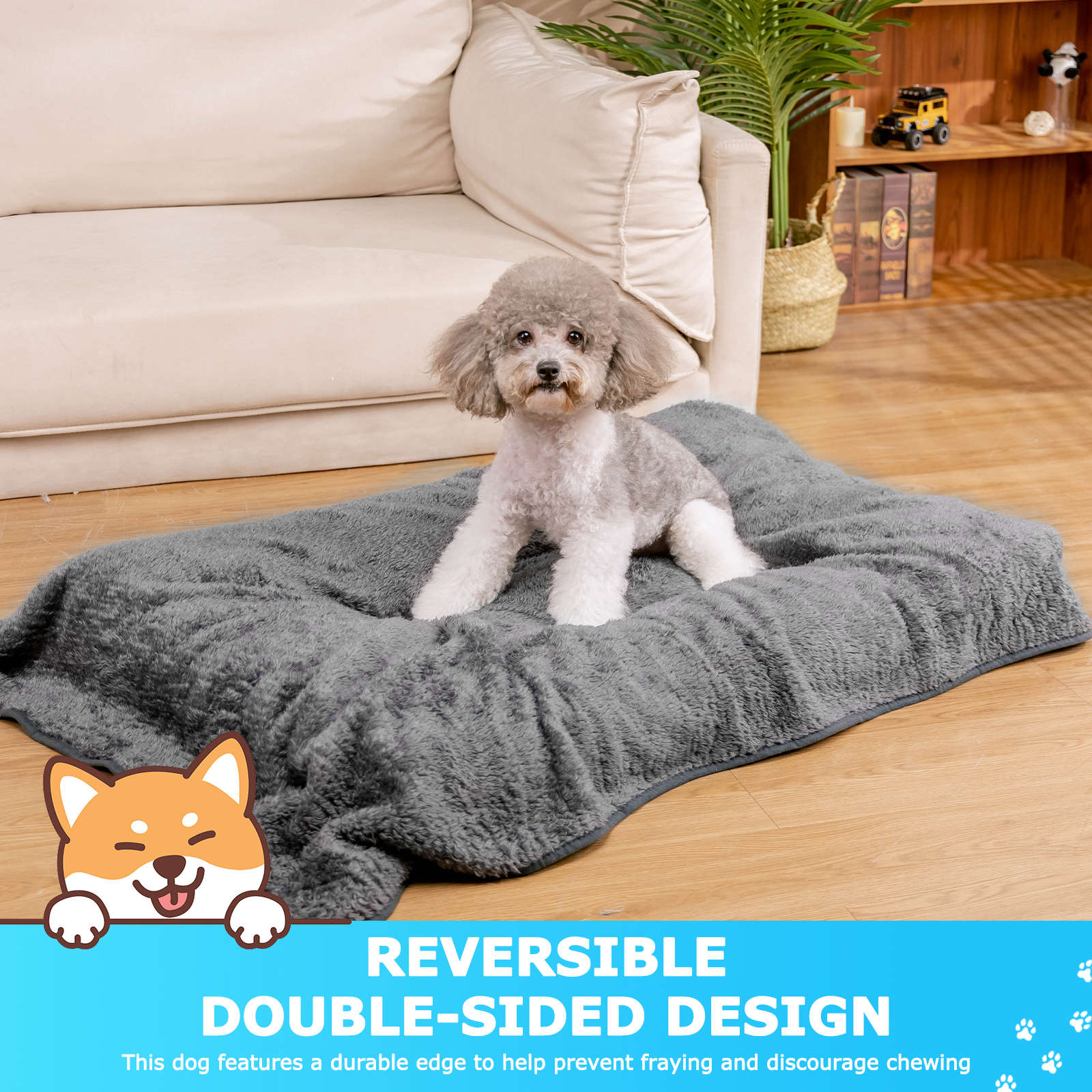 Un perro pequeño en una cama gris y esponjosa con un diseño de doble cara, el texto 'REVERSIBLE' está presente.