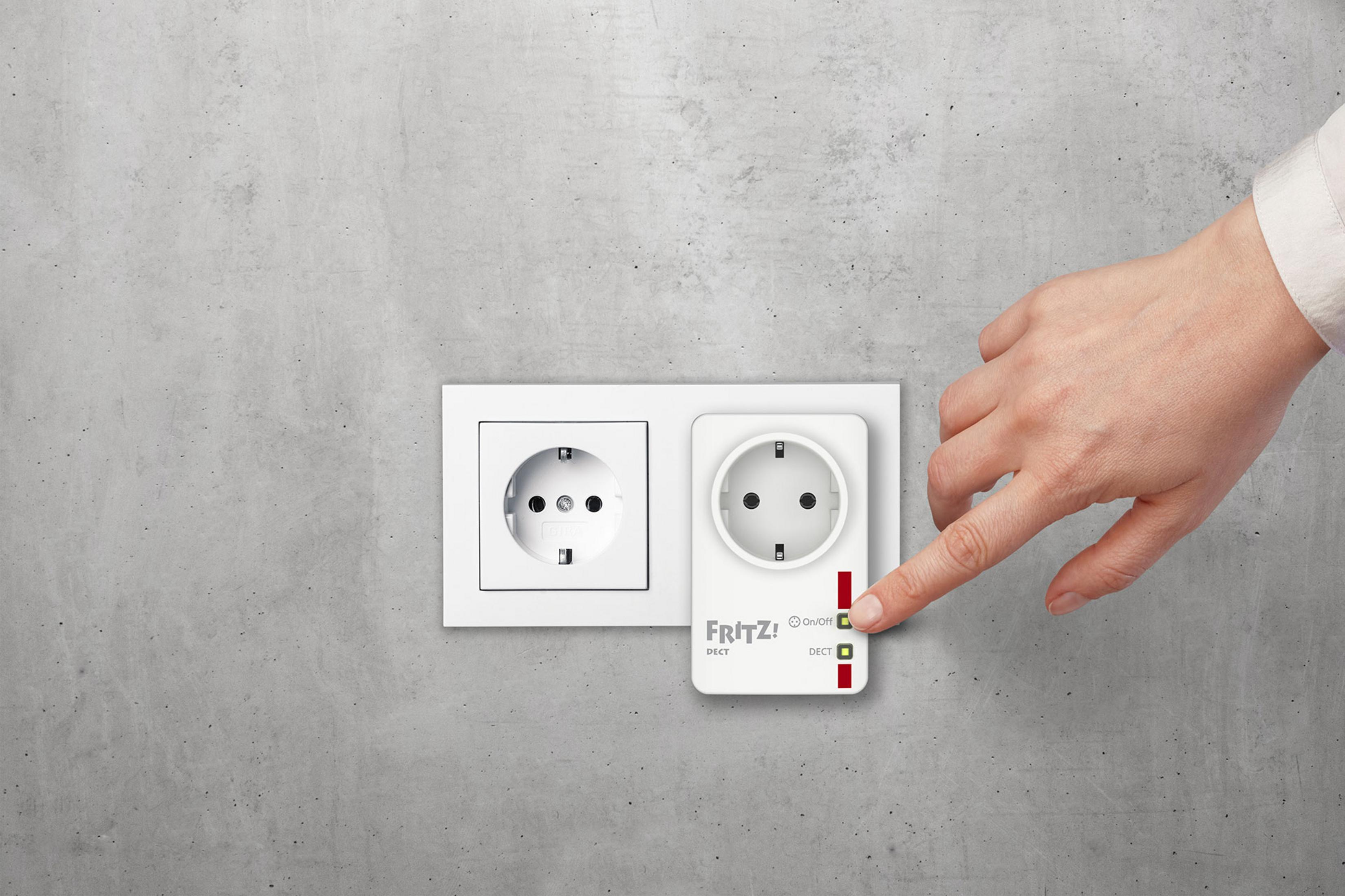 Steckdose mit weißem Adapter, mit einem Finger, der auf den Einschaltknopf zeigt.