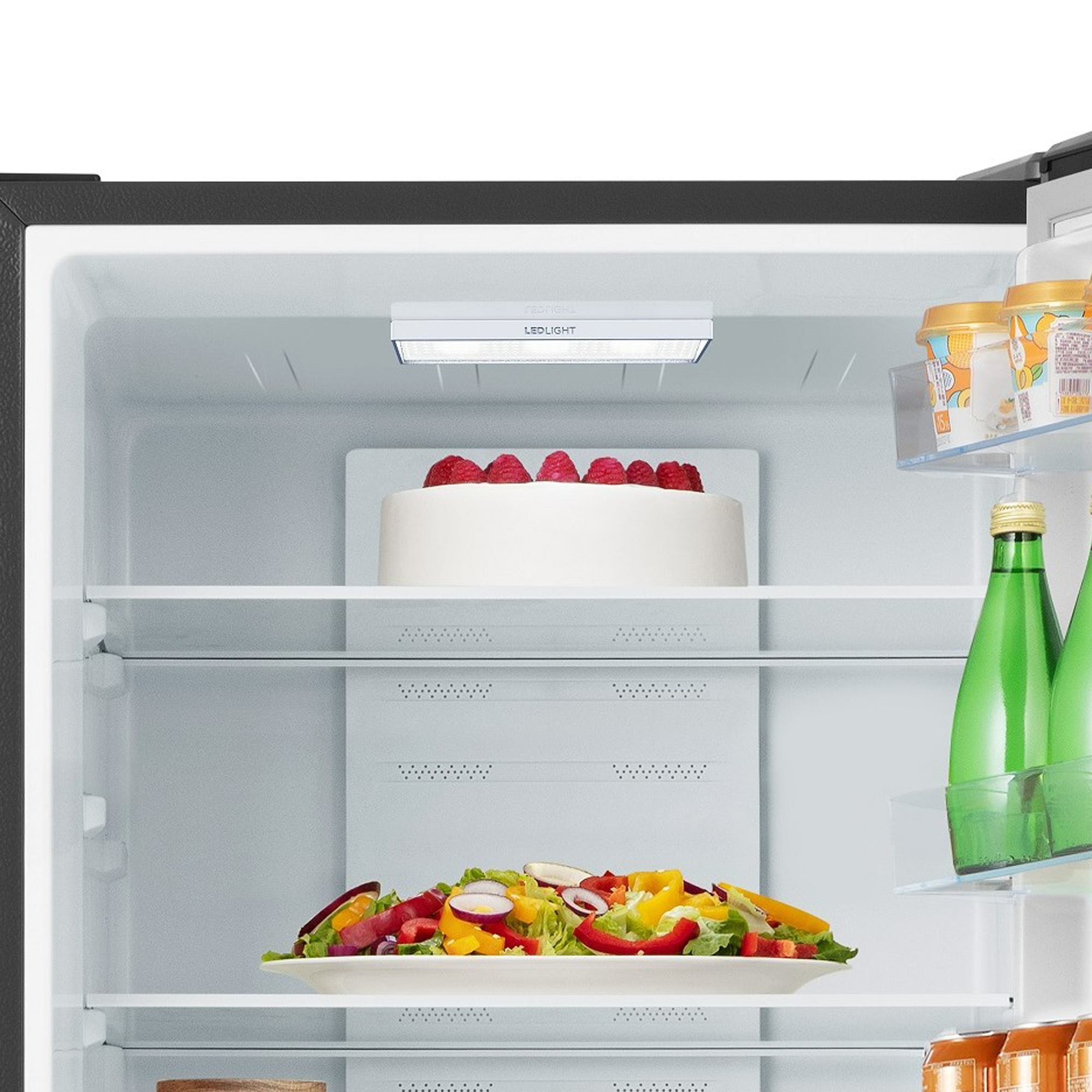 In einem Kühlschrank: Kuchen, Salat und Wasserflaschen auf Regalen.