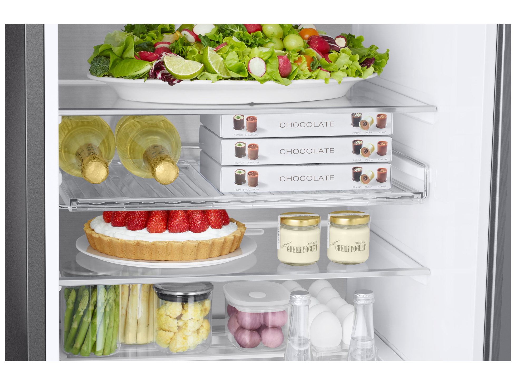 Kühlschrankinnenraum. Salat, Schokoladenboxen, Champagner, Joghurt und andere Lebensmittel.