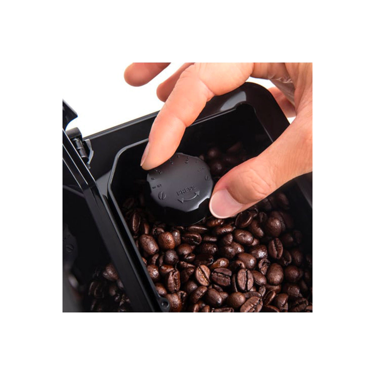 Die Hand einer Person drückt einen schwarzen, runden Deckel auf einen Behälter mit Kaffeebohnen.