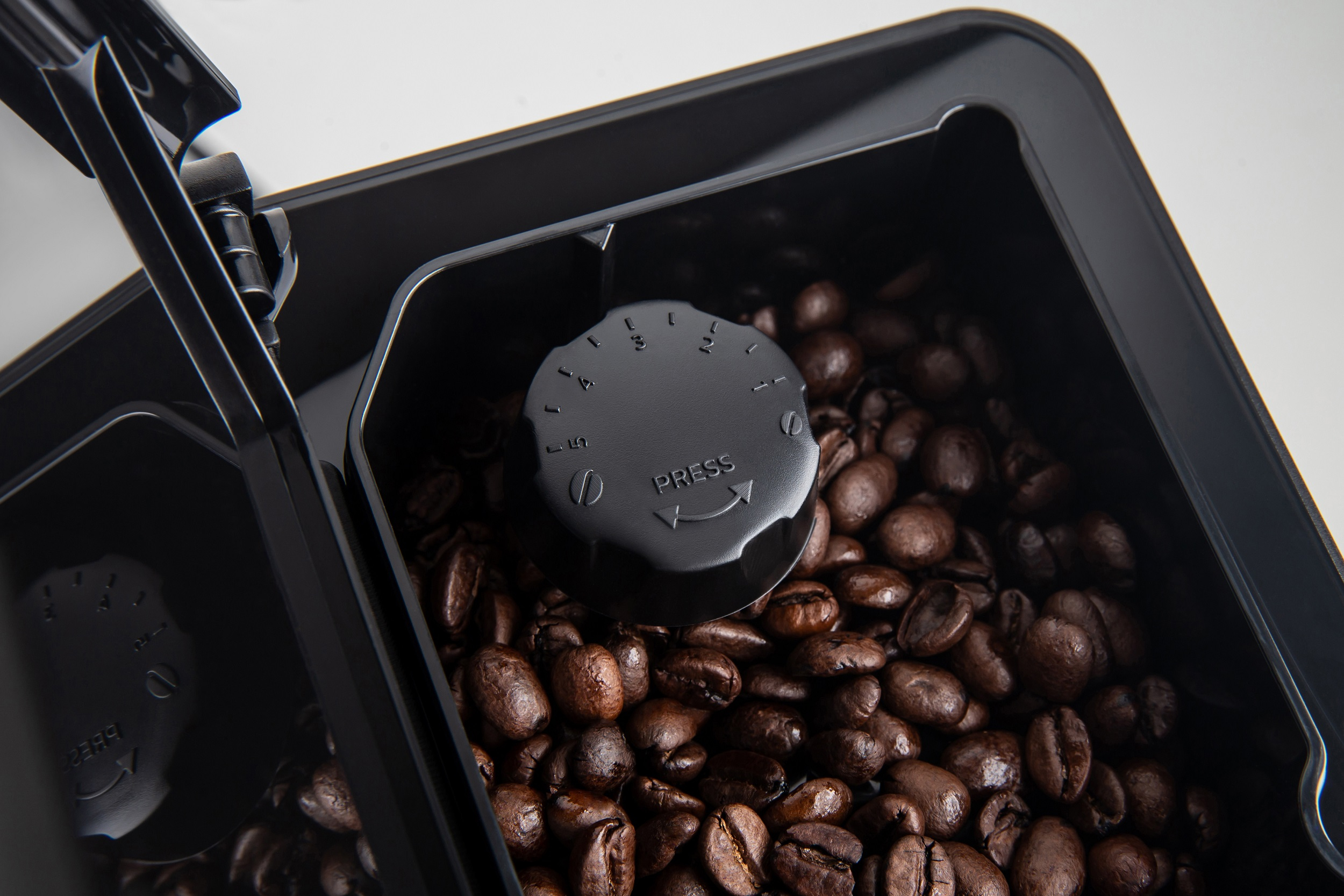 Schwarzer Kaffeebohnenbehälter gefüllt mit Kaffeebohnen, mit einem Drehregler oben.