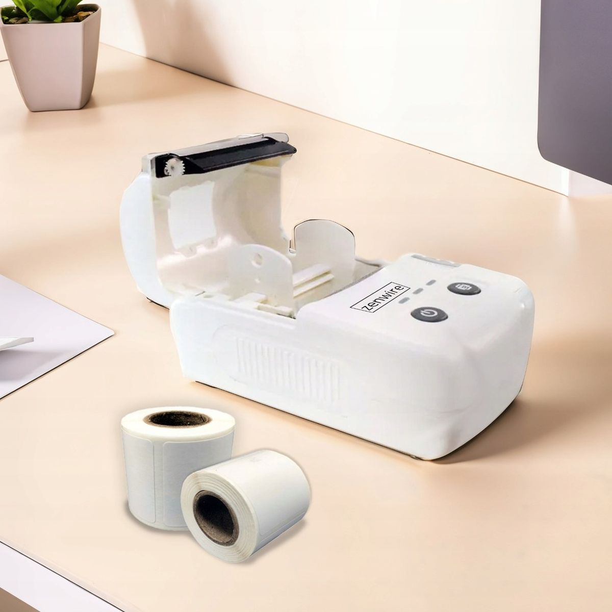 Biała drukarka etykiet z rolkami etykiet na jasnym biurku.