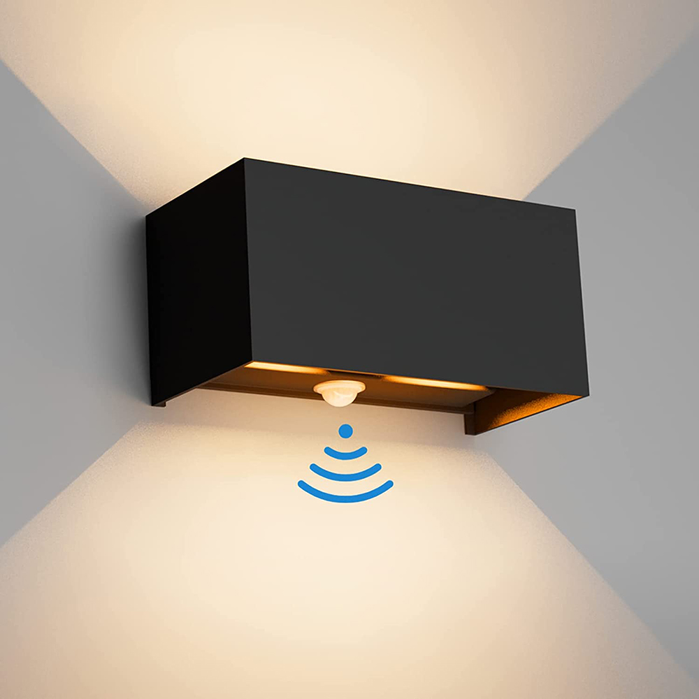 Schwarze Außenwandleuchte mit Bewegungsmelder, die Licht auf eine Wand wirft.