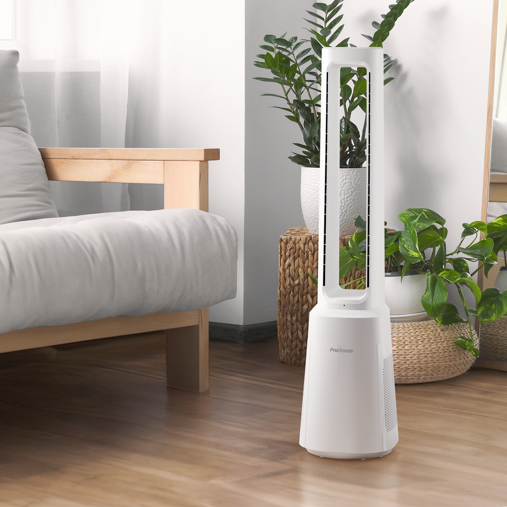Weißer Turmventilator in einem Wohnzimmer. Pflanzen und eine Couch im Hintergrund.