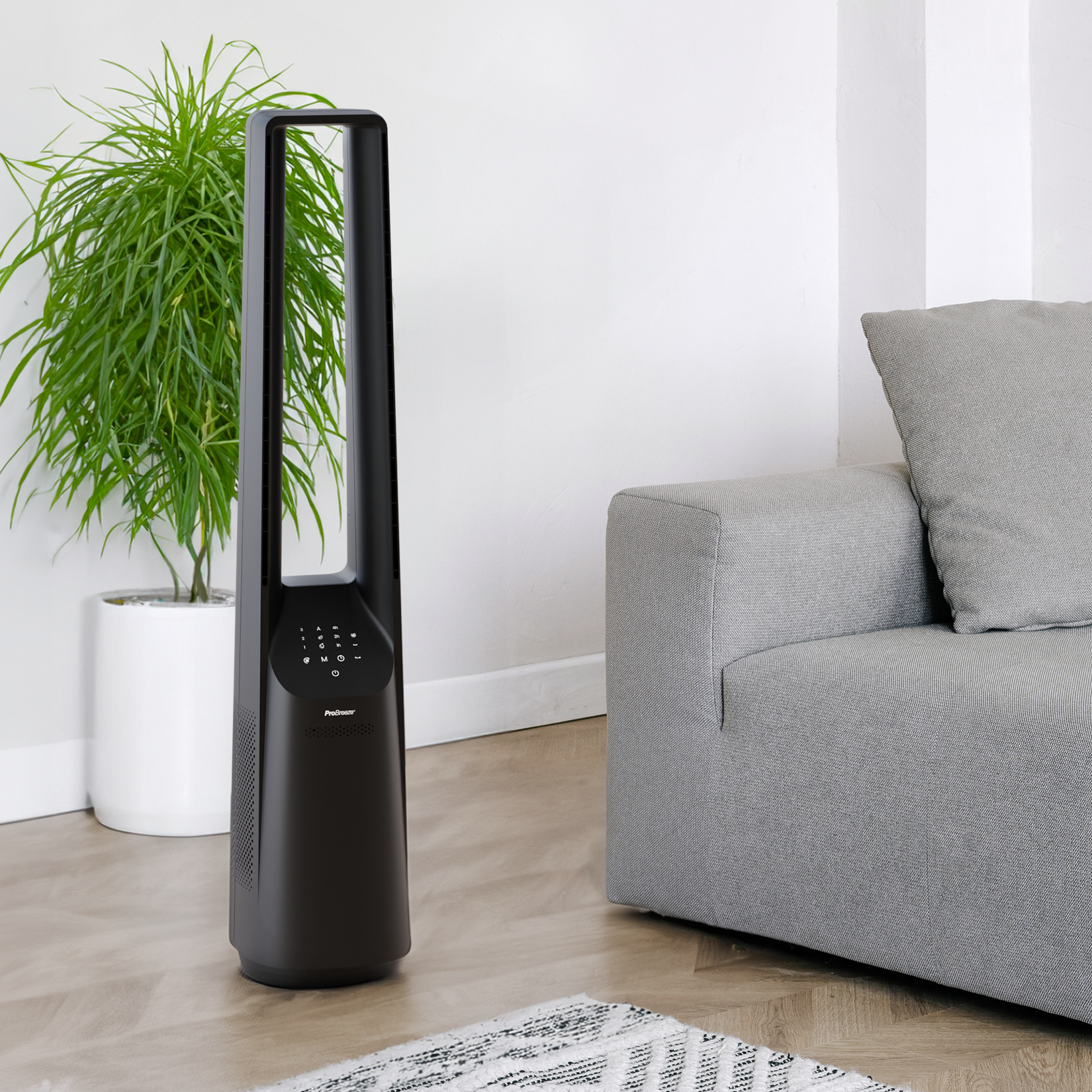 Schwarzer Standventilator, Pflanze und graues Sofa in einem Raum.