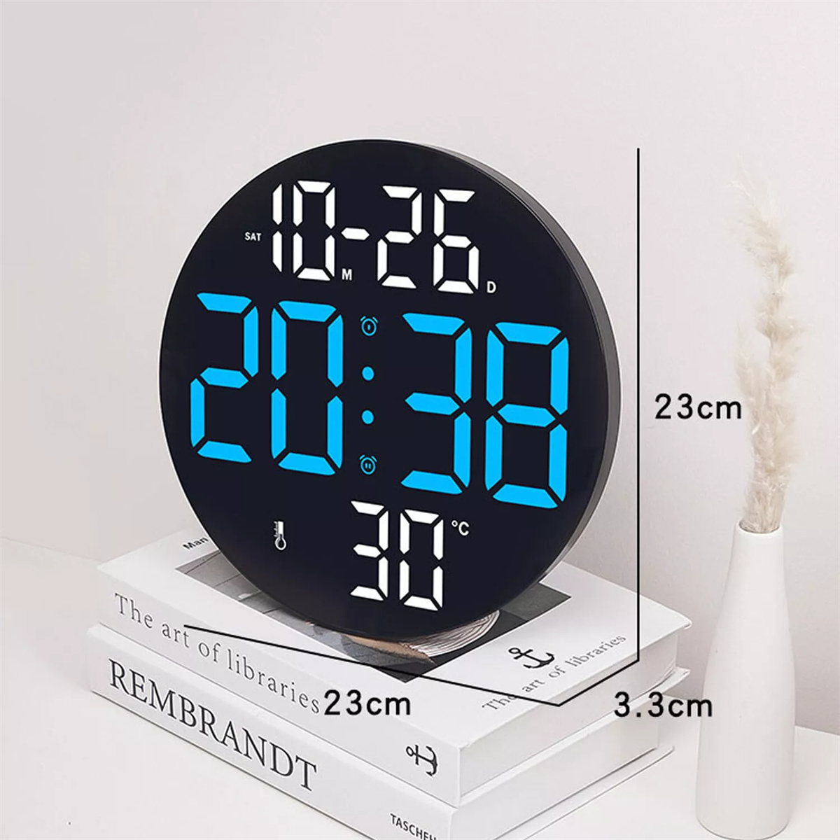 Schwarze Digitaluhr mit 20:38, 10-26 und 30°C, auf Büchern.