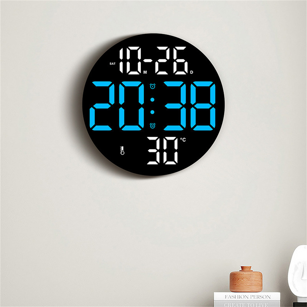 Schwarze Uhr zeigt Zeit, Datum und Temperatur an einer weißen Wand. Holzdekor darunter.