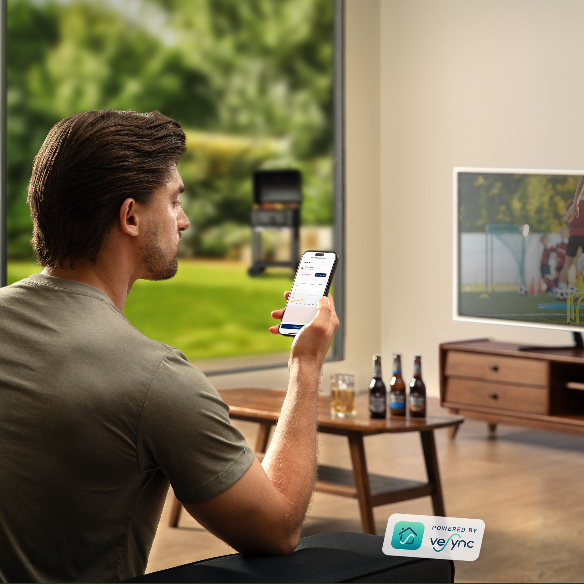 Hombre mirando el teléfono, cerveza y vaso en la mesa, TV al fondo. El logo de la app es visible.