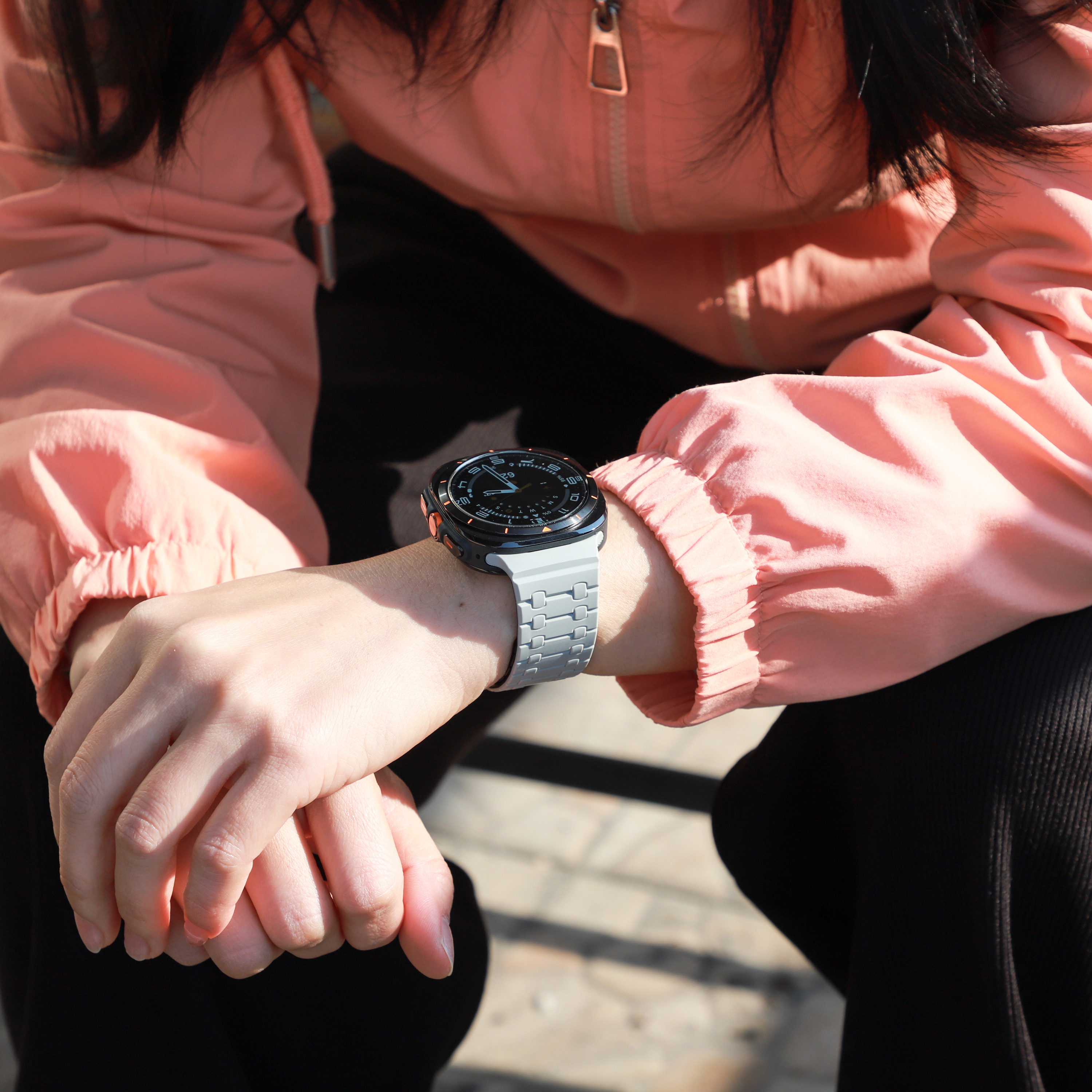 Handgelenk einer Person mit Uhr, Hände sichtbar, im Sonnenlicht sitzend.