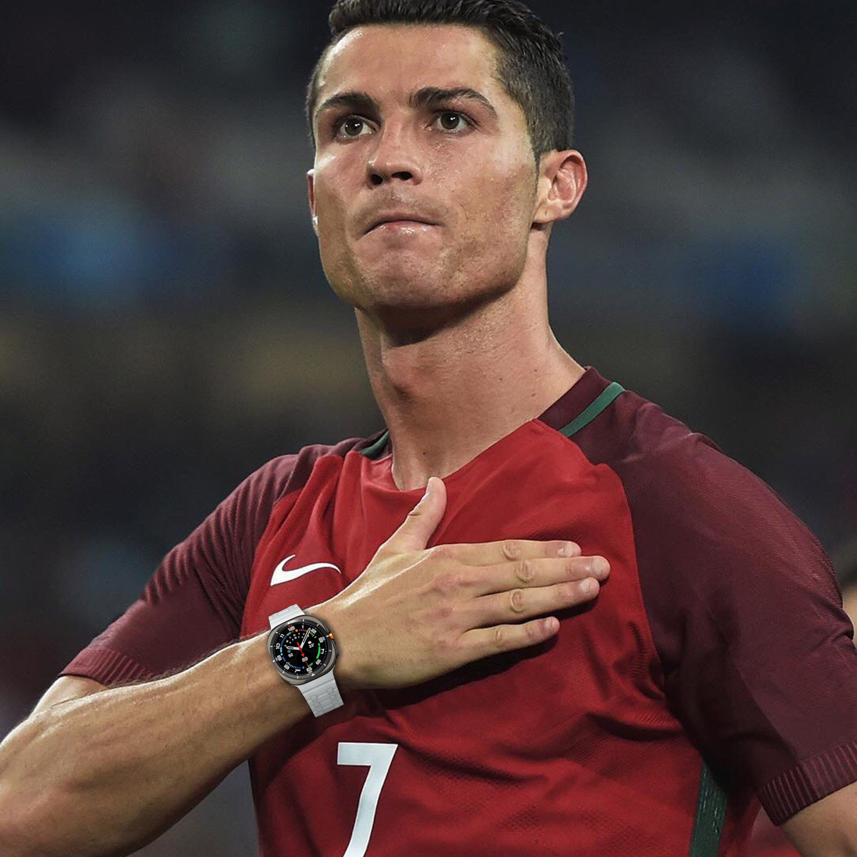 Cristiano Ronaldo trägt eine Uhr, Hand auf der Brust, vor grünem Hintergrund.