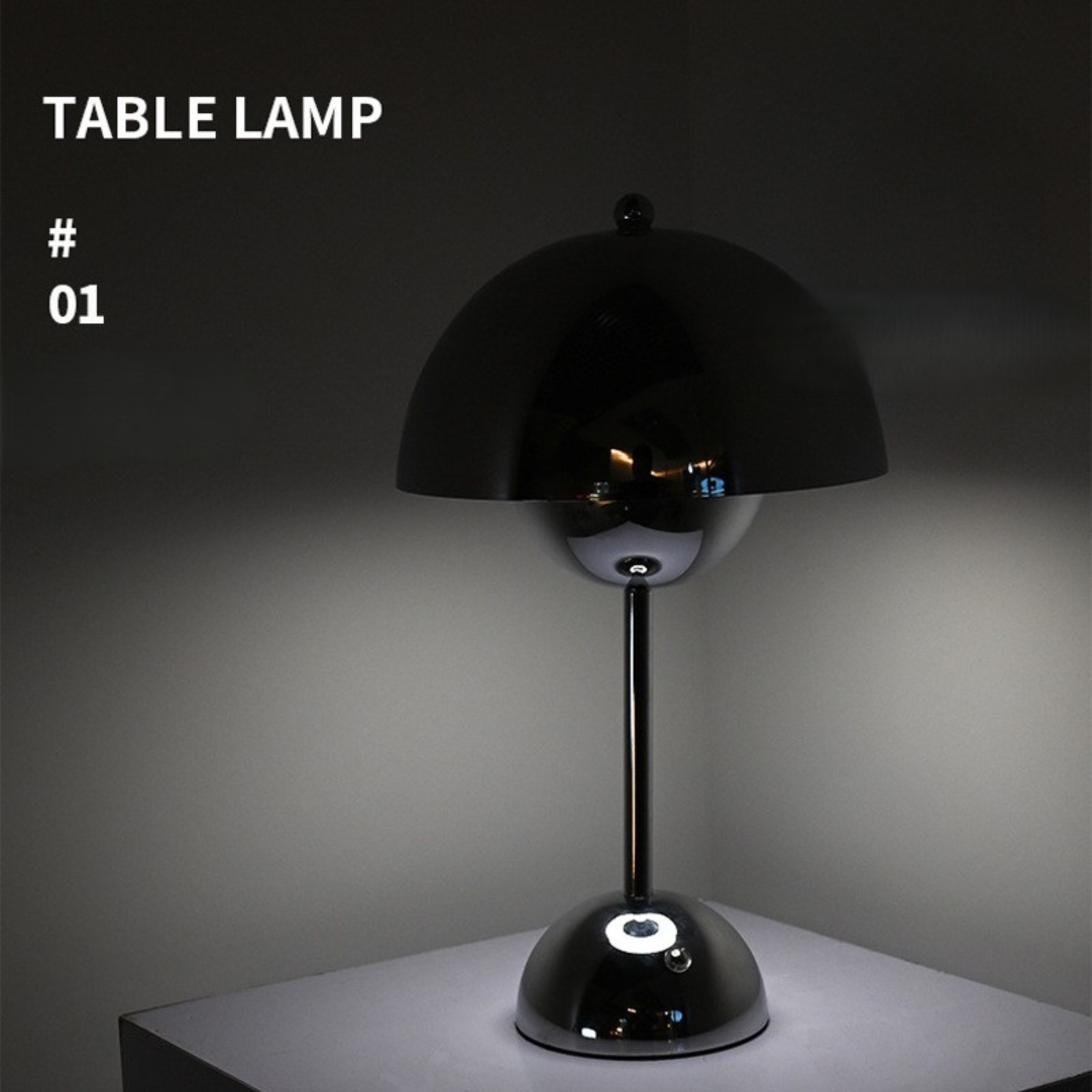 Schwarze Tischlampe mit Chromsockel und rundem Schirm. Die Lampe steht auf einer weißen Oberfläche.