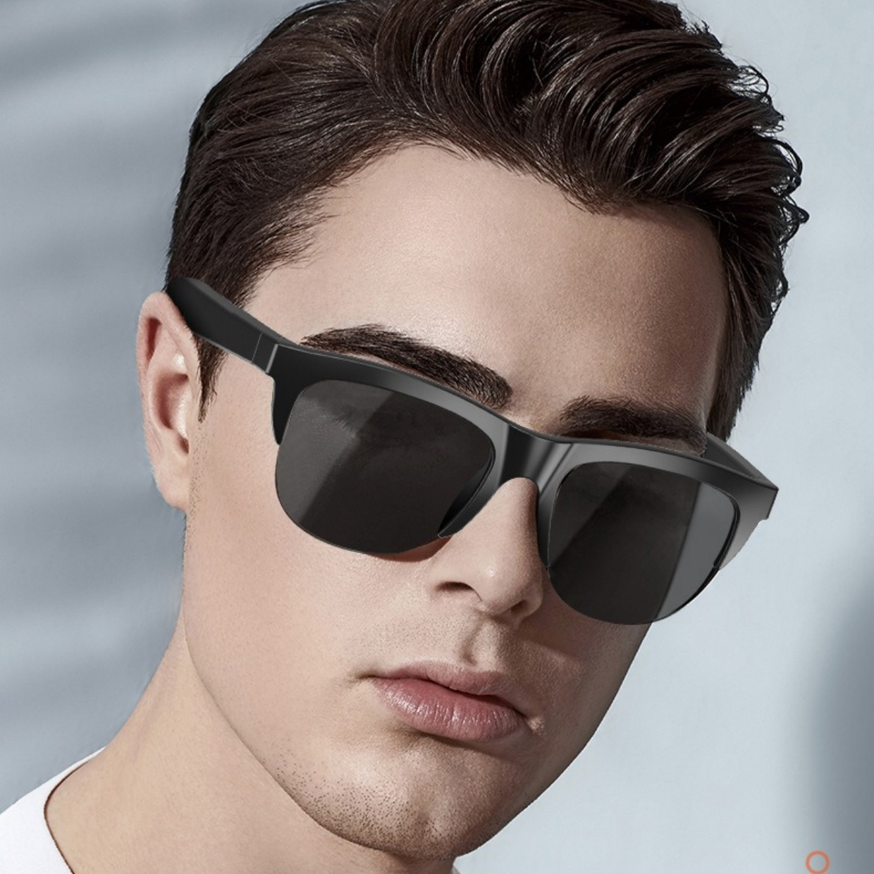 Ein Mann trägt eine schwarze Sonnenbrille. Er hat kurze dunkle Haare und schaut nach vorne.