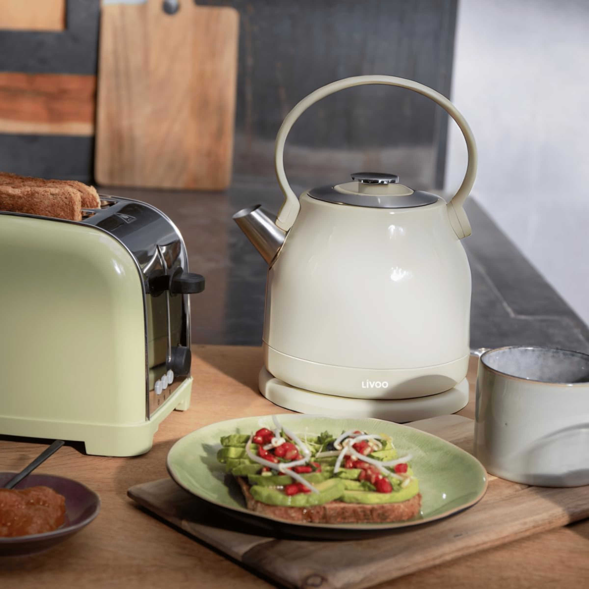 Eine Küchenszene mit Toaster, Wasserkocher und einem Teller mit Avocado-Toast auf einer Holzoberfläche.