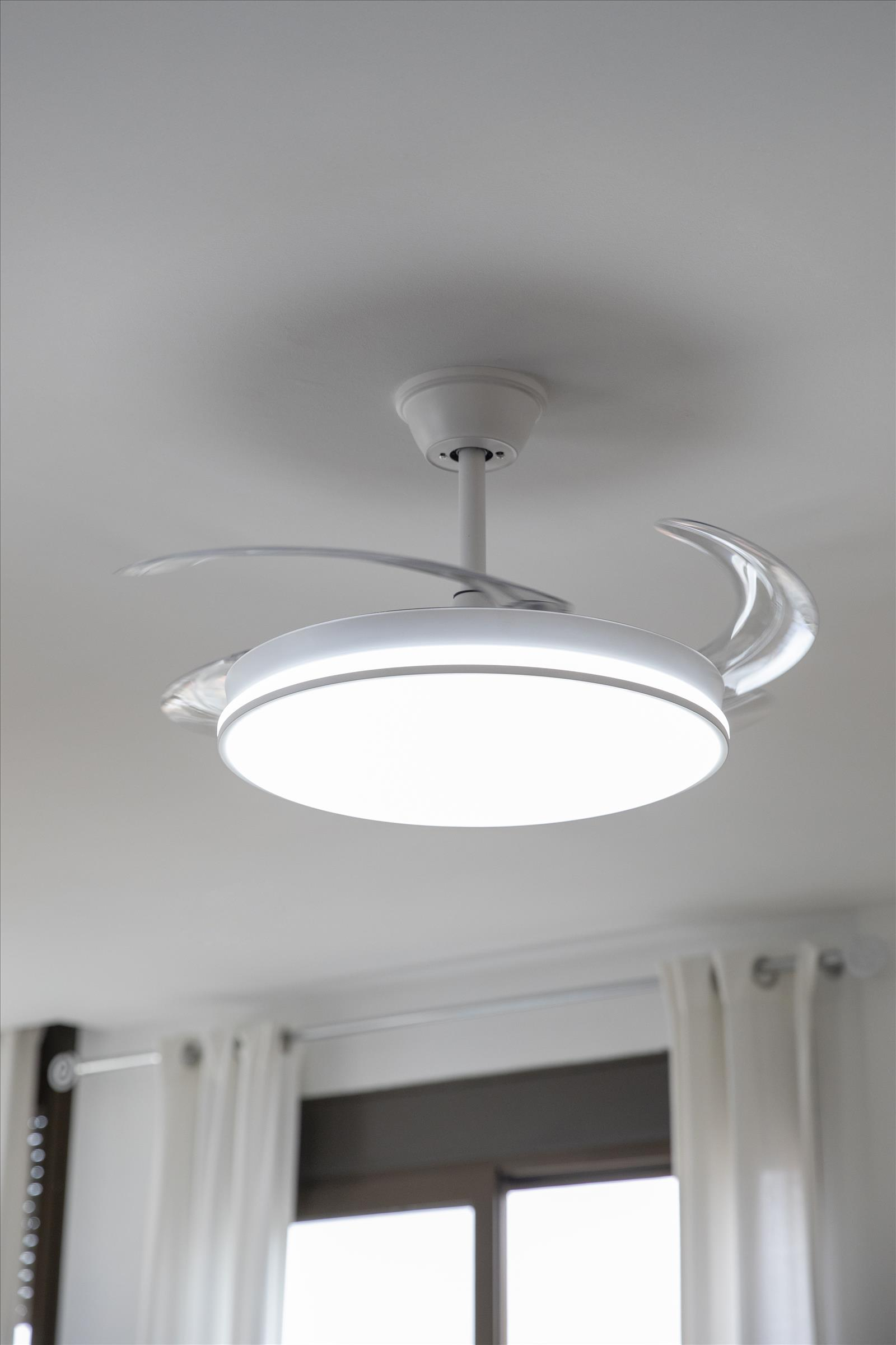 Ventilador de techo blanco con luz central y aspas curvas, interior brillante.
