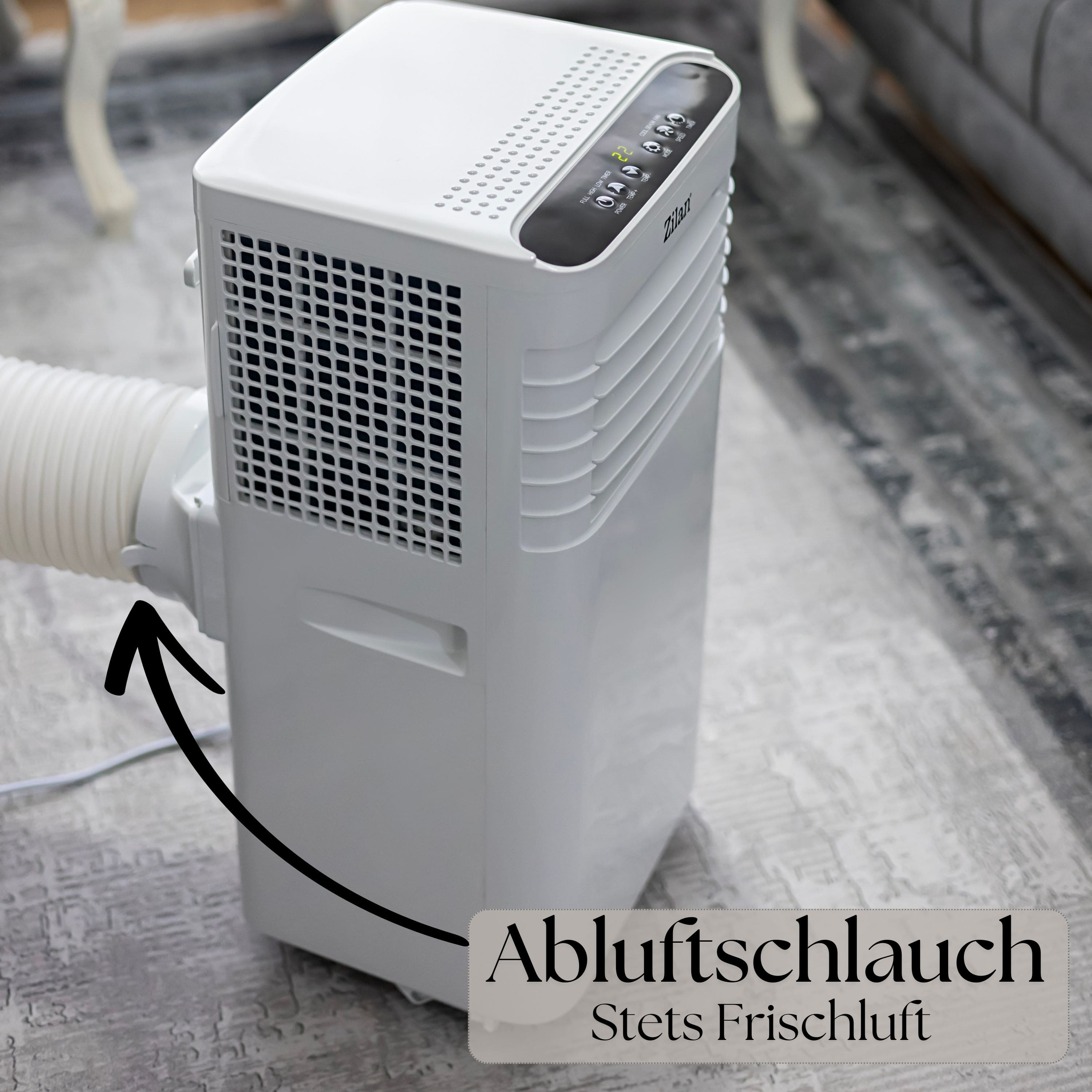 Ein weißer tragbarer Klimaanlage mit angeschlossenem Abluftschlauch. Steht auf einem Teppich.