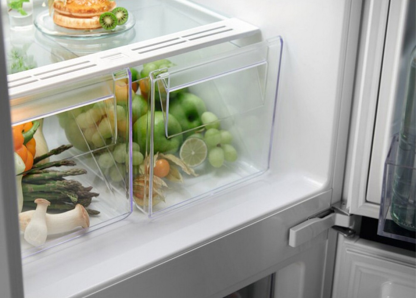 Interno del frigorifero con contenitori per verdure. Frutta e verdura visibili.