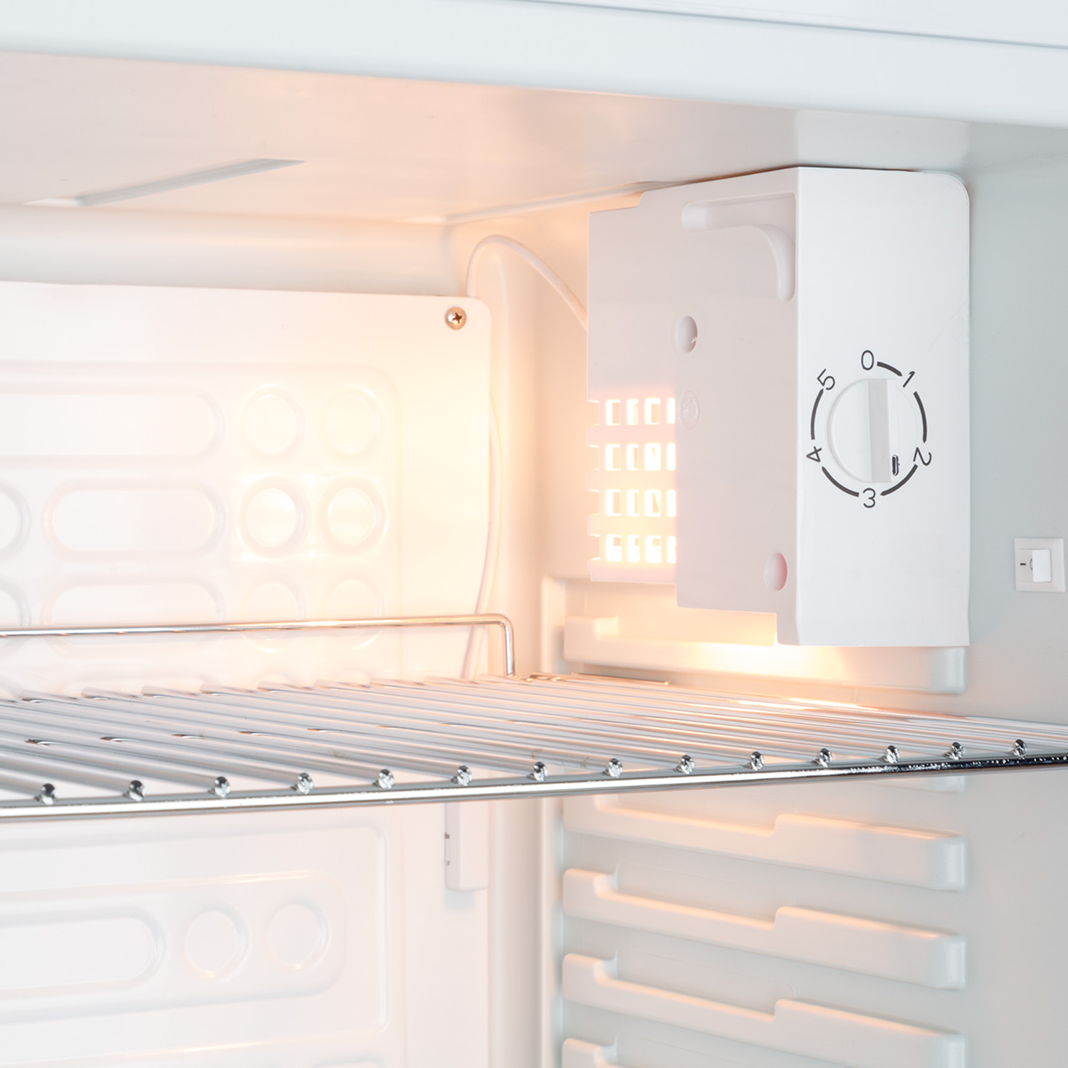 Kühlschrankinnenraum mit Licht an, zeigt ein Regal und einen Temperaturregler.
