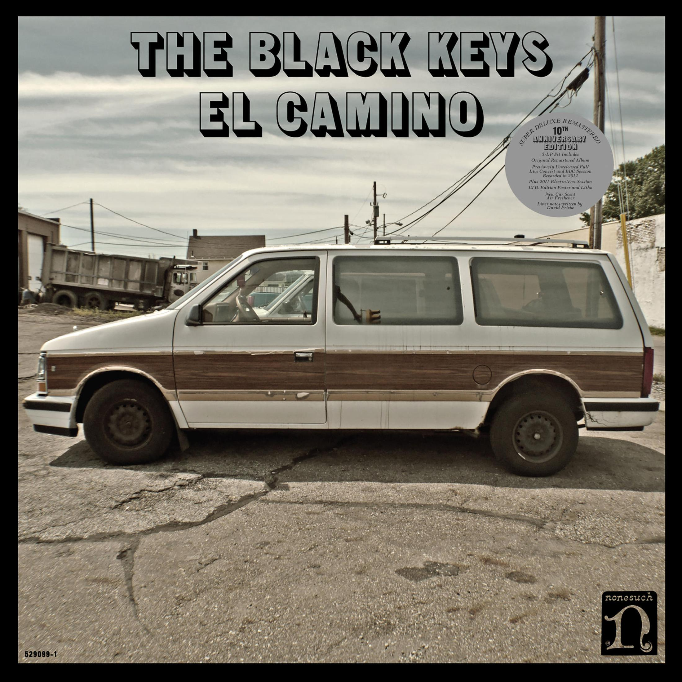 Albumhoes: Een witte bestelwagen met houten panelen geparkeerd op een straat, getiteld "El Camino" van The Black Keys.