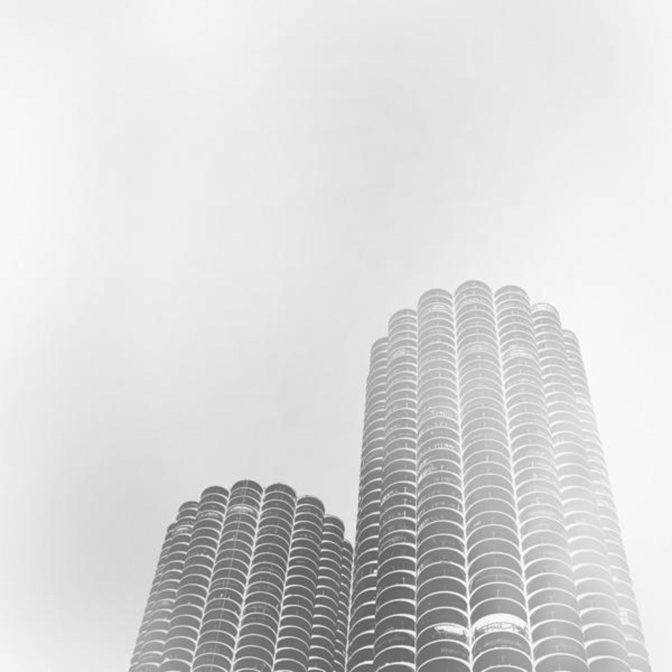 Copertina dell'album: Due edifici alti con un design cilindrico contro un cielo nuvoloso.