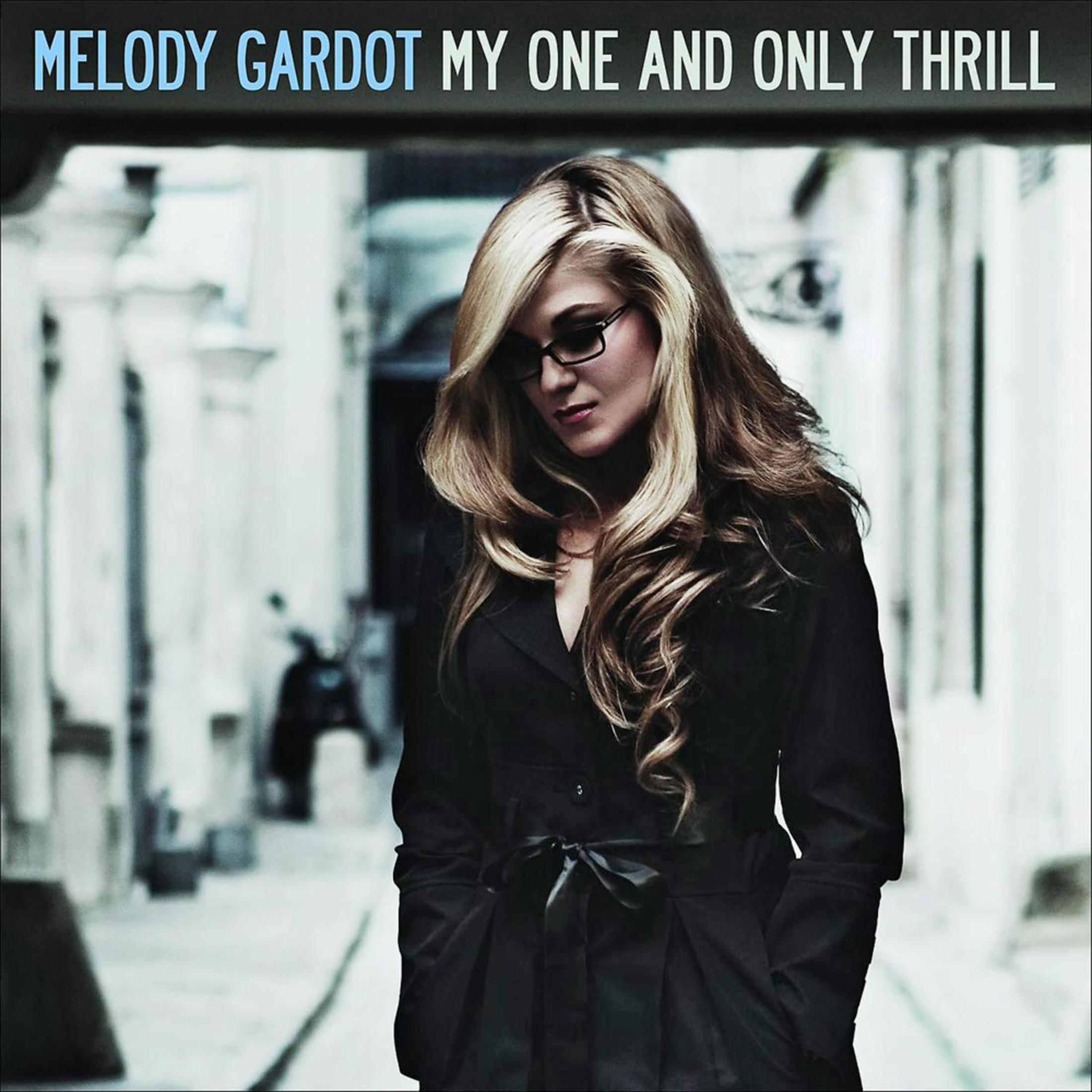 Copertina dell'album di Melody Gardot. Donna in cappotto nero, occhiali, cammina per strada.