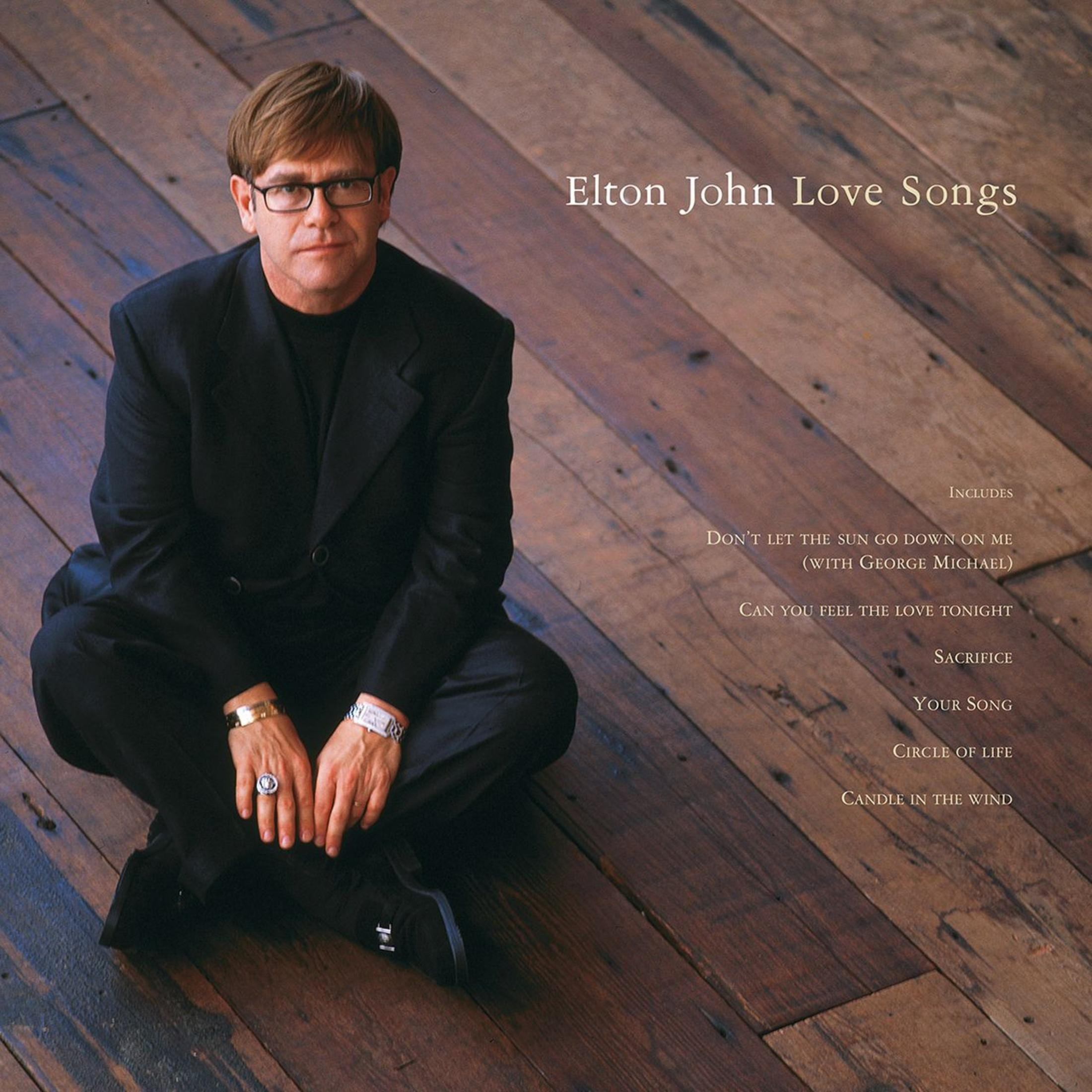 Albumhoes: Elton John, in zwart pak, zittend op hout. Het album is Elton John Love Songs.