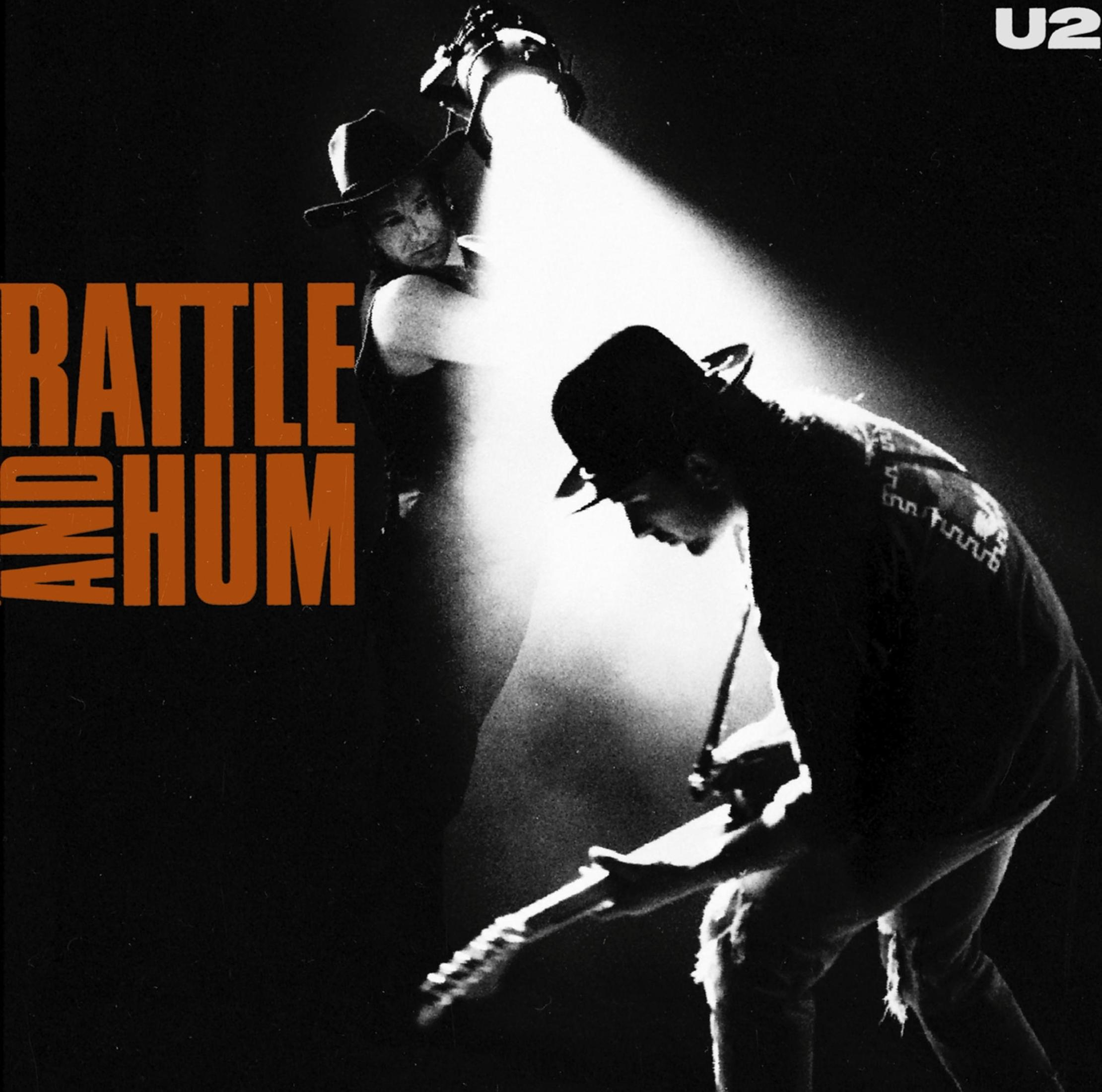 Copertina dell'album degli U2, due membri della band in abiti scuri e cappelli sotto un riflettore.
