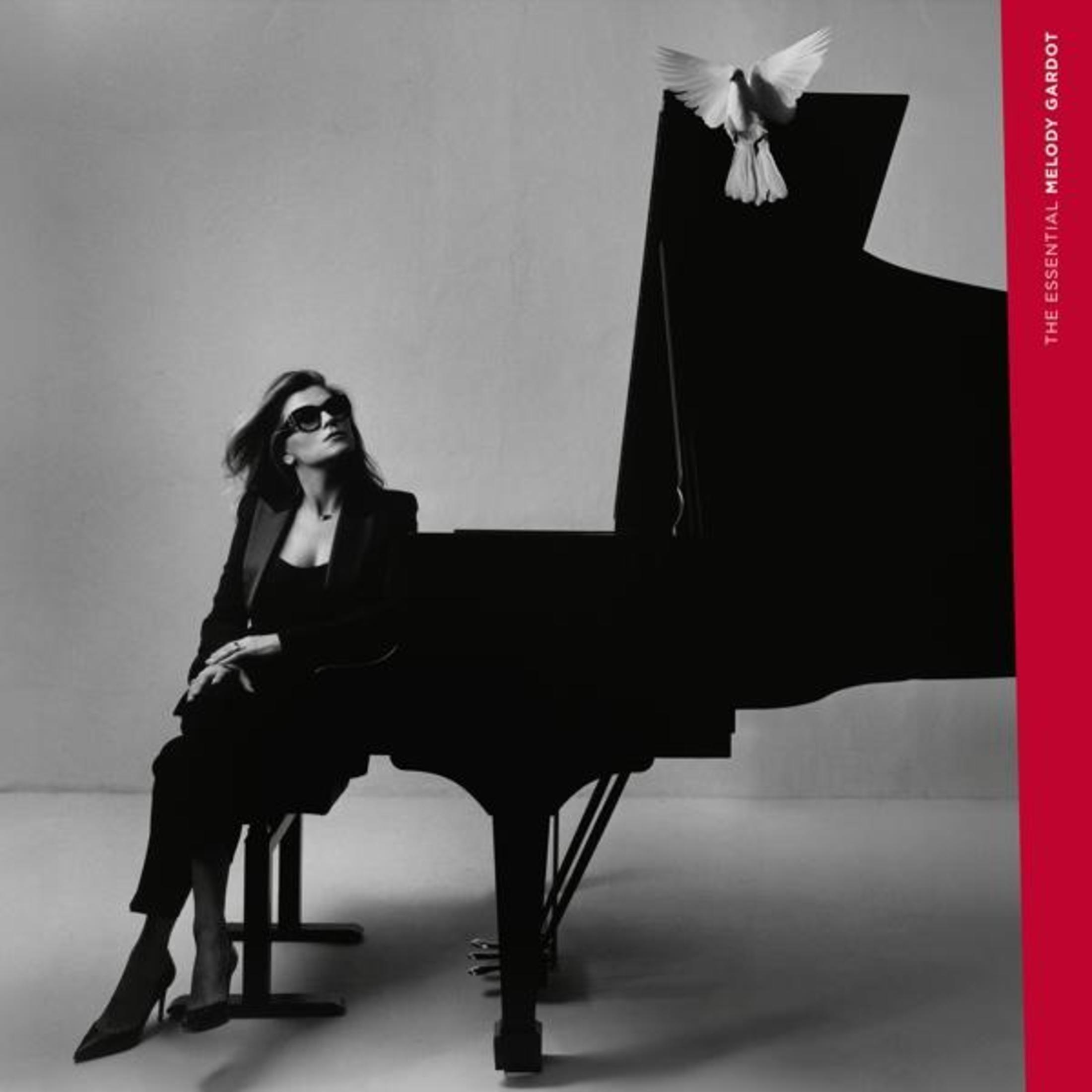 Copertina dell'album: Donna con occhiali da sole seduta vicino a un pianoforte e una colomba. Titolo: The Essential Melody Gardot.