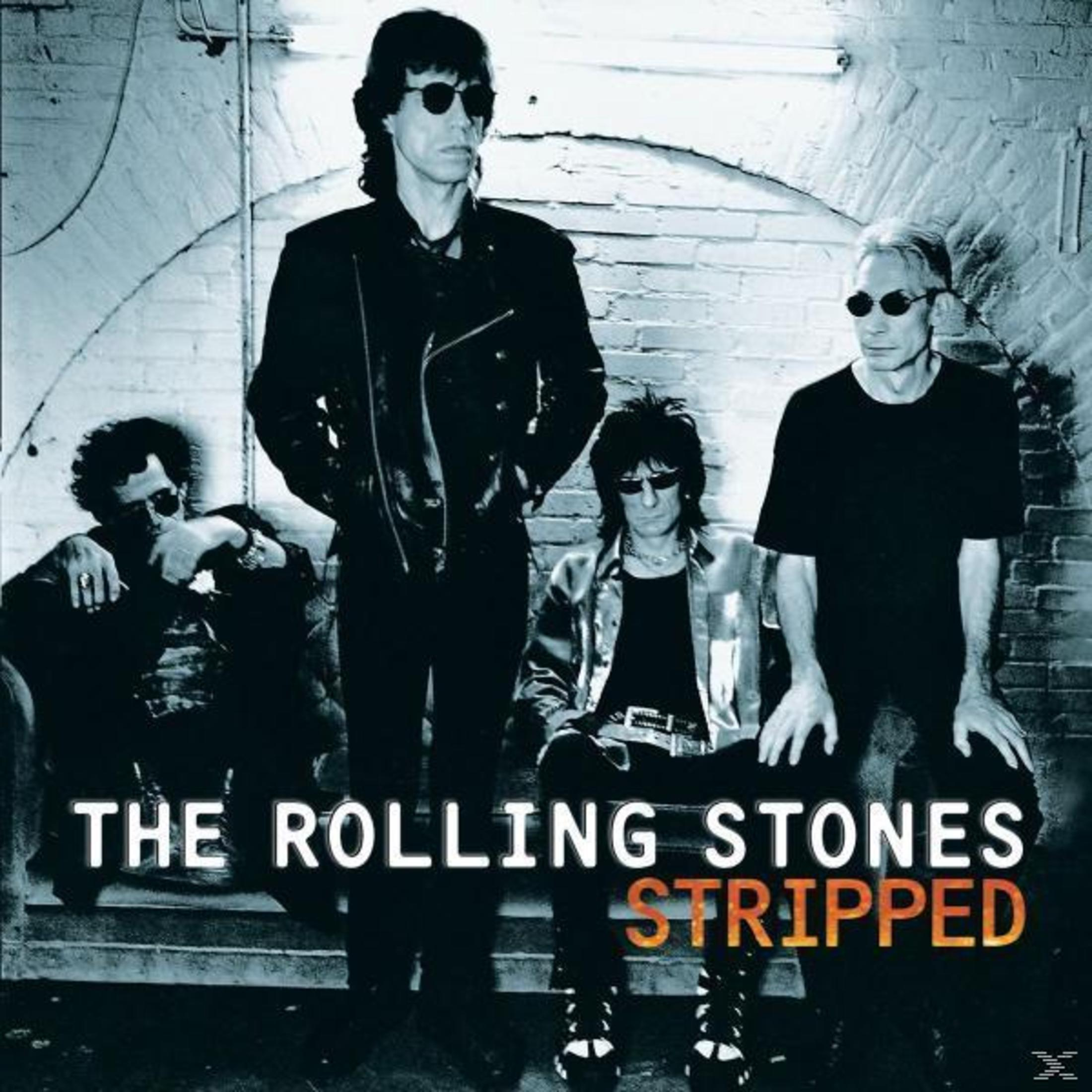 Copertina dell'album. The Rolling Stones, quattro uomini in abiti scuri, occhiali da sole, sfondo in mattoni e testo.