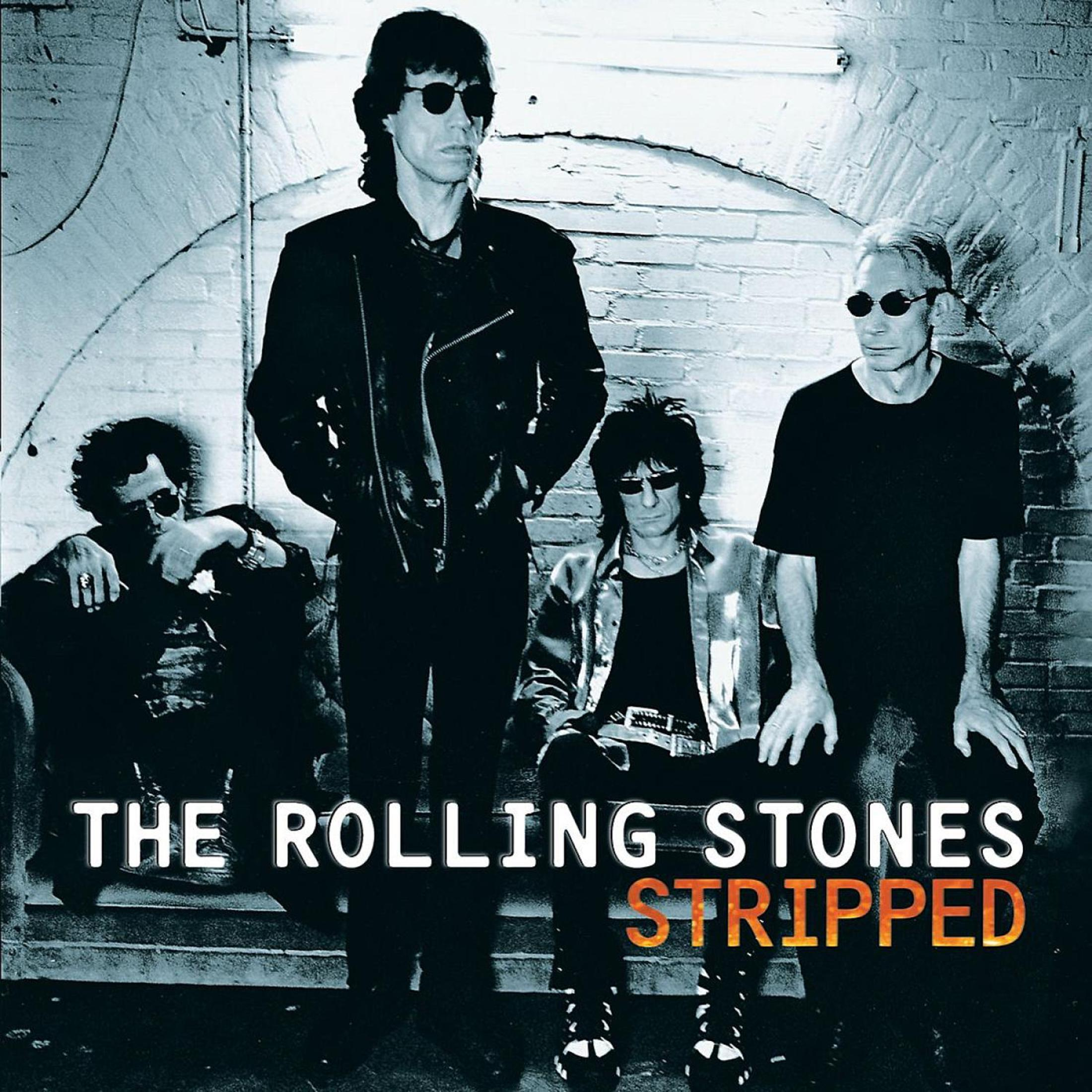 La copertina dell'album dei Rolling Stones con quattro membri della band di fronte a un muro di mattoni. Foto in bianco e nero.