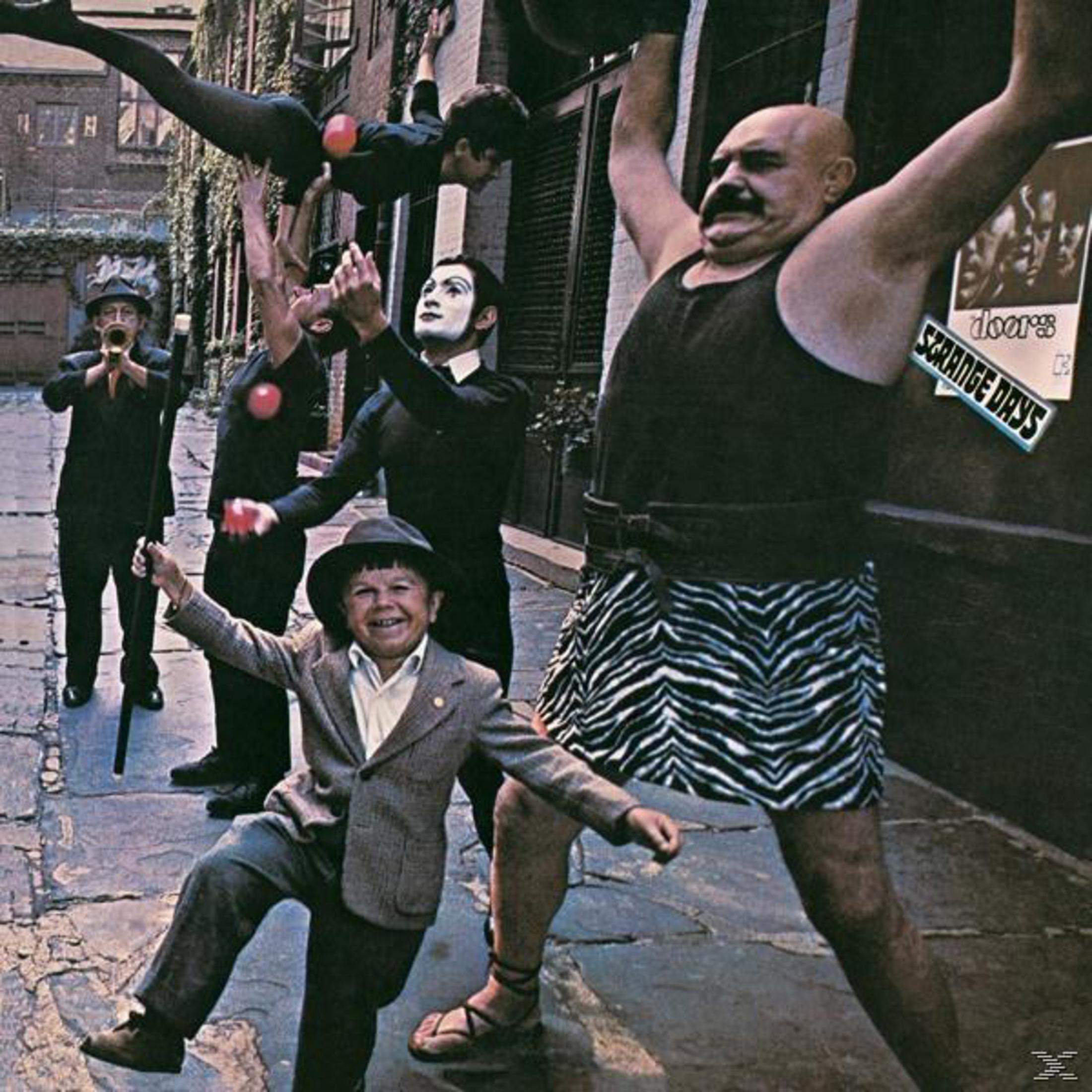 Copertina dell'album, diversi uomini in varie pose, uno con la testa calva e la gonna zebrata, altri che fanno i giocolieri e suonano strumenti.